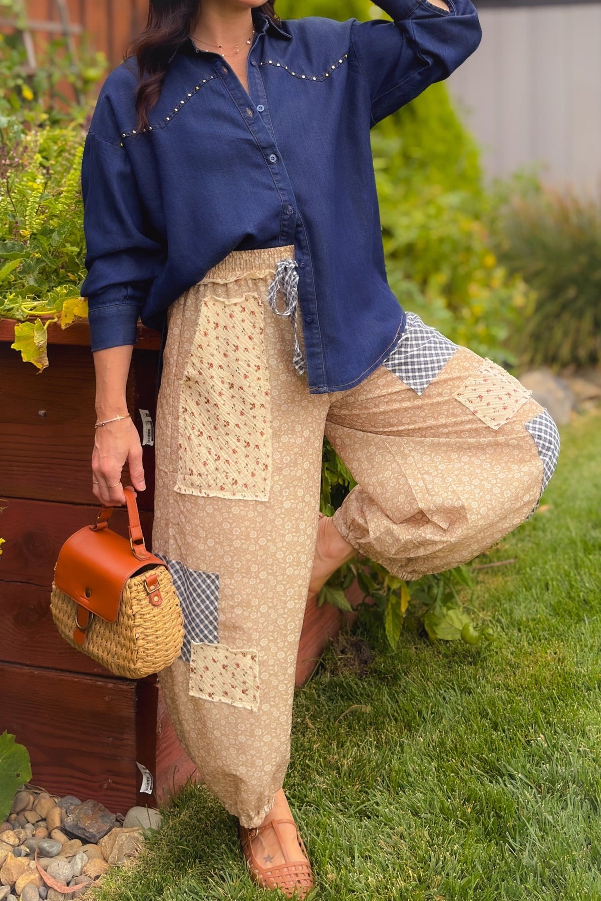 Close-up of beige floral patchwork balloon pants with navy gingham and cream floral panels, styled with a cream toggle knit cardigan and woven flats.