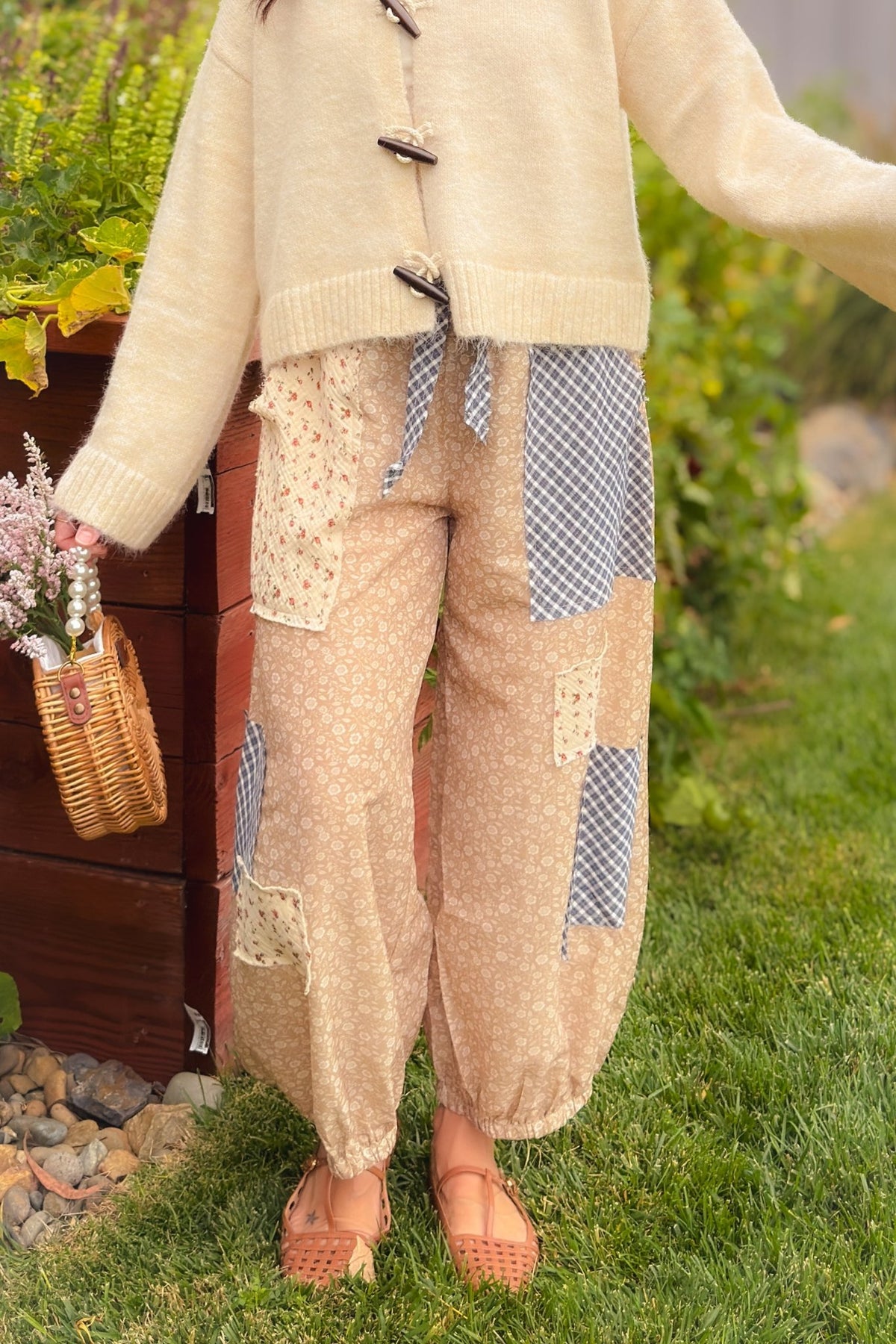 Full-length view of beige floral patchwork balloon pants featuring mixed floral and navy gingham panels, relaxed balloon legs and gathered elastic hems.