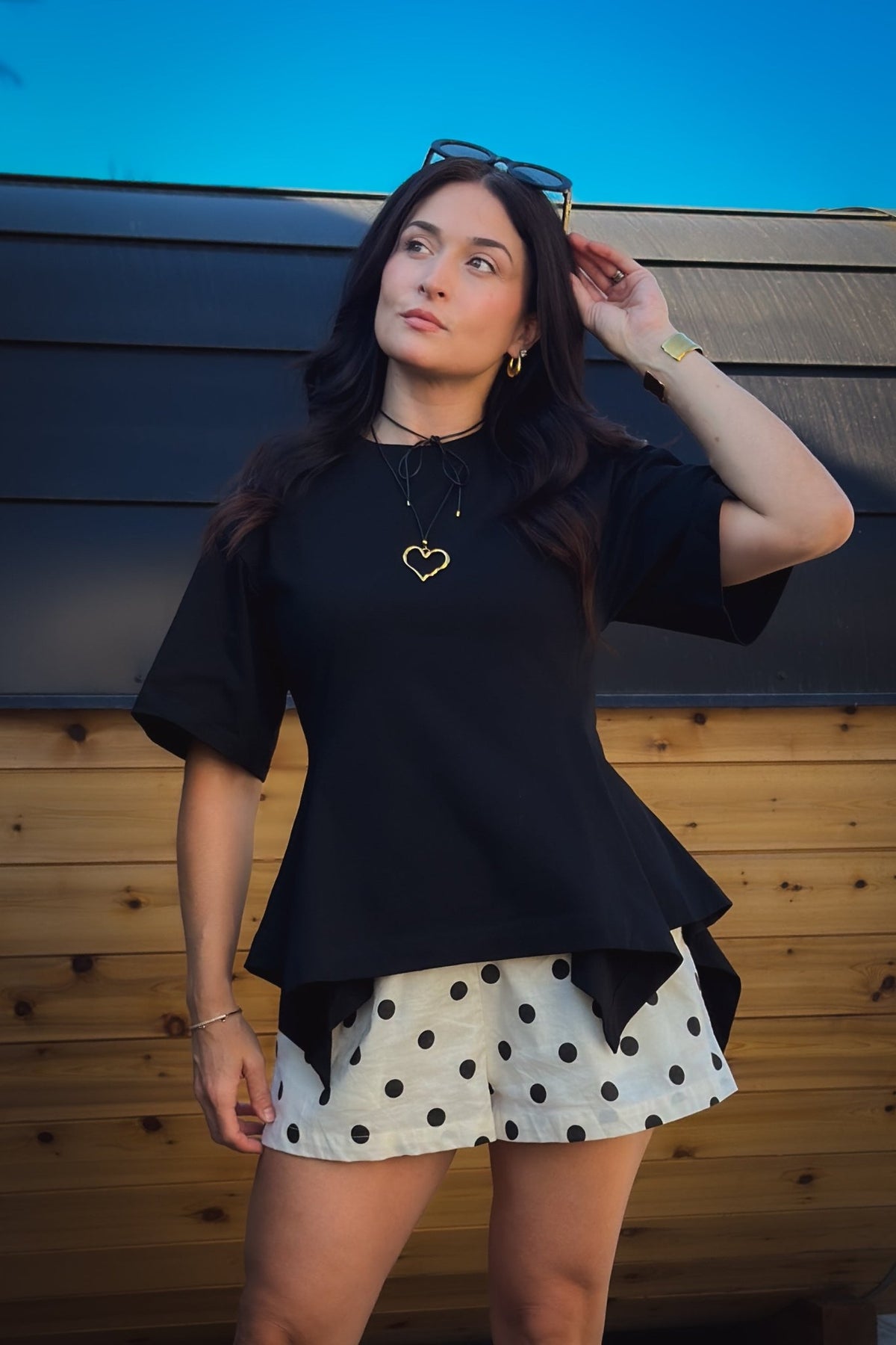 Black structured cotton top with oversized sleeves, fitted waist and a softly flared peplum hem.