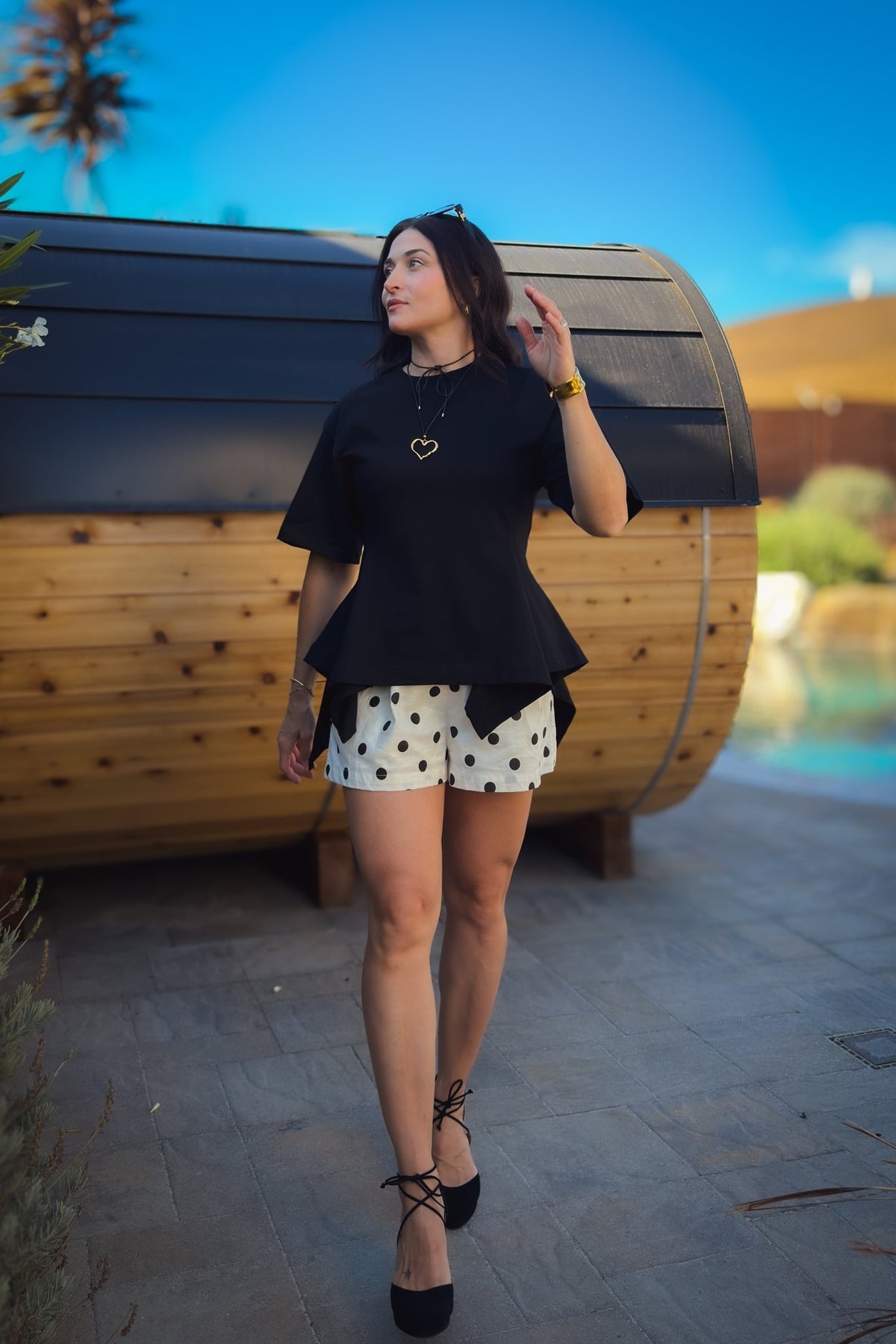 Back view of black structured cotton peplum top showing the fitted waist and flared hemline.