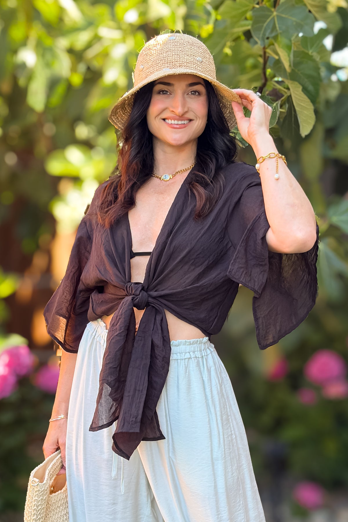 Close-up detail of a black tie front kimono cover up top with flutter sleeves and lightweight crinkle texture.
