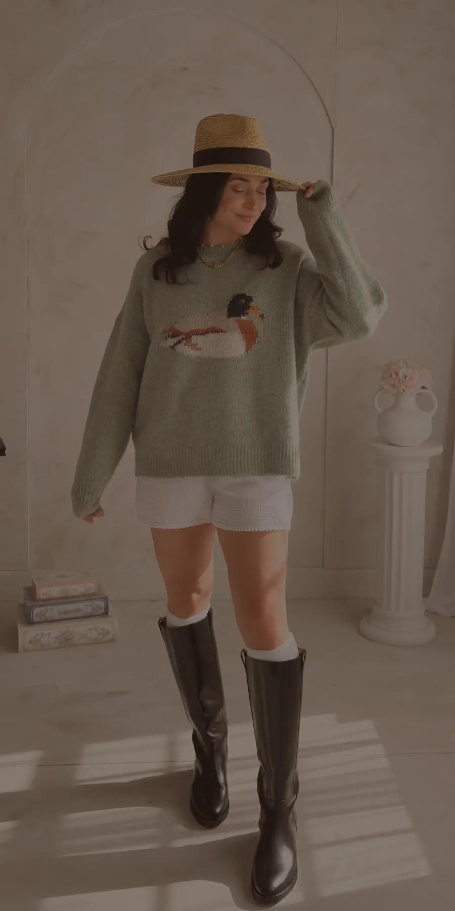 Woman wearing sage green duck sweater with straw hat and boots styled for feminine everyday fashion at Blooming Daily women’s boutique