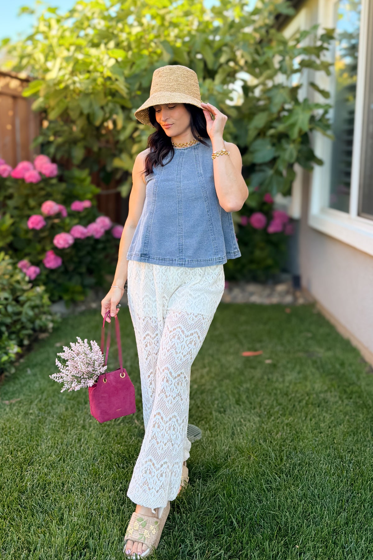 Blue denim swing tank top for women paired with ivory lace pants and a floral handbag for a garden party outfit.
