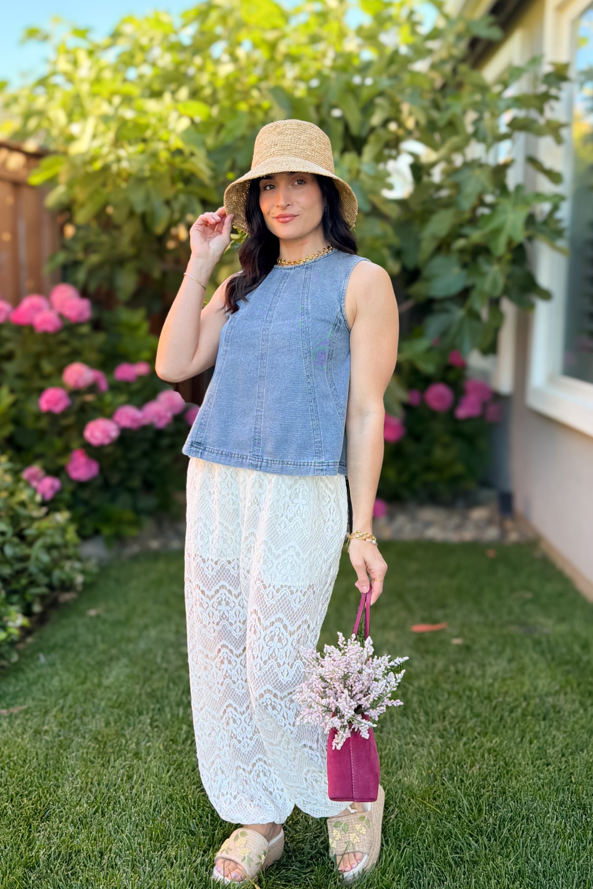 Medium wash blue denim swing tank top styled with lace pants and a woven bucket hat in a garden-inspired summer look.