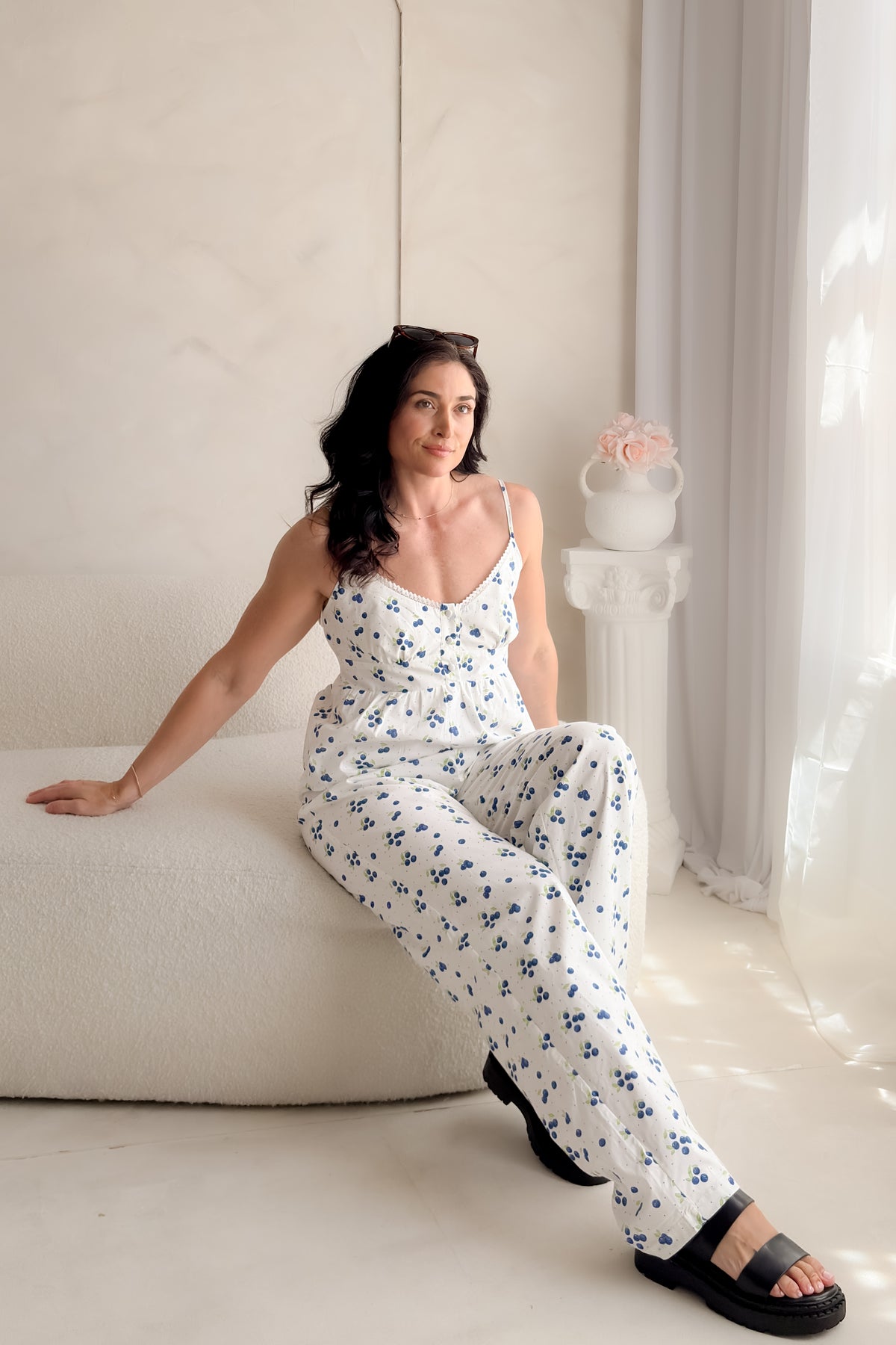 Woman wearing white blueberry print cotton poplin pants with decorative button fly, soft elastic waistband, wide-leg silhouette, and relaxed summer styling.