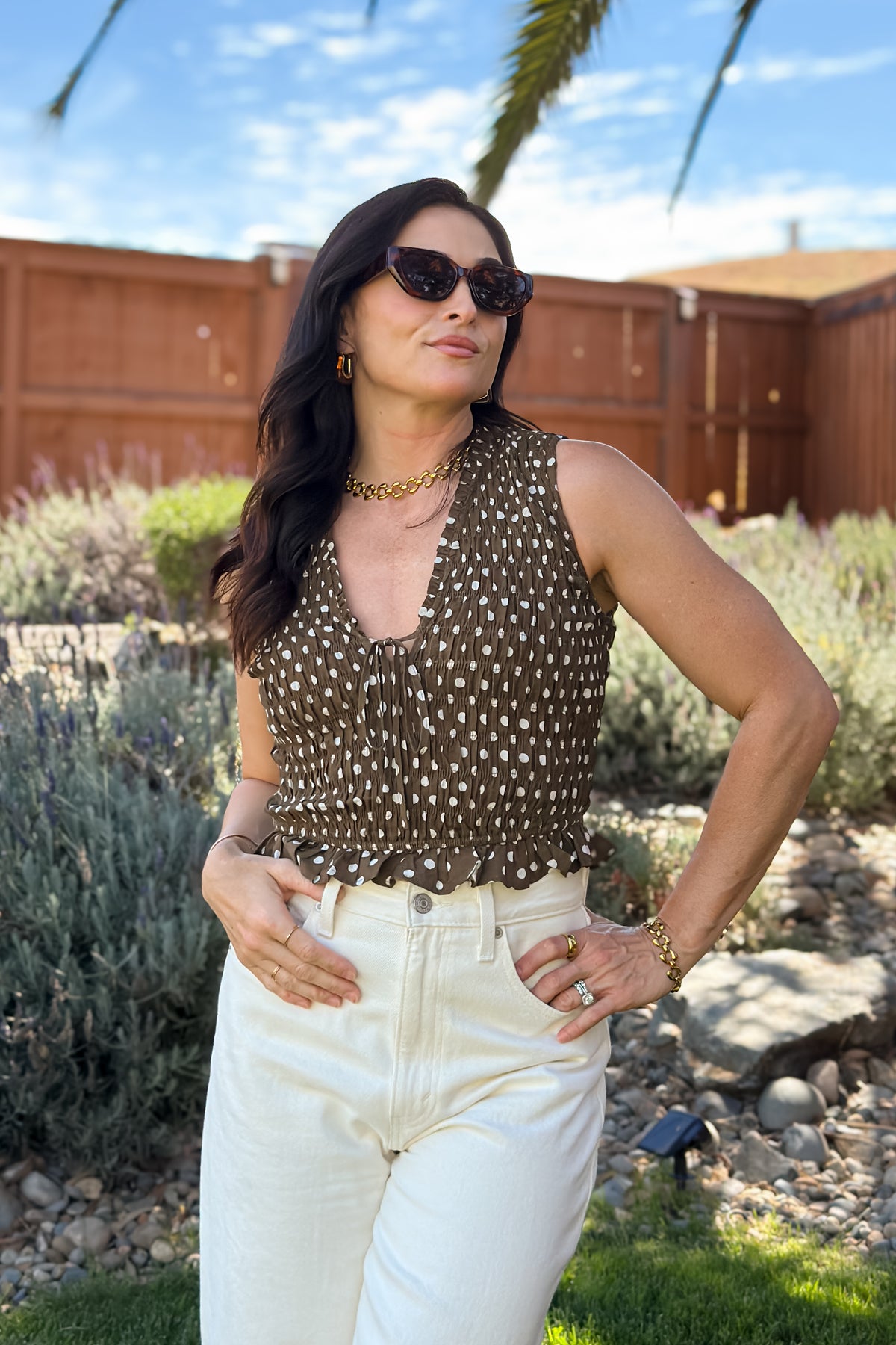 Brown polka dot smocked top styled with high-waisted cream denim for a feminine casual outfit.