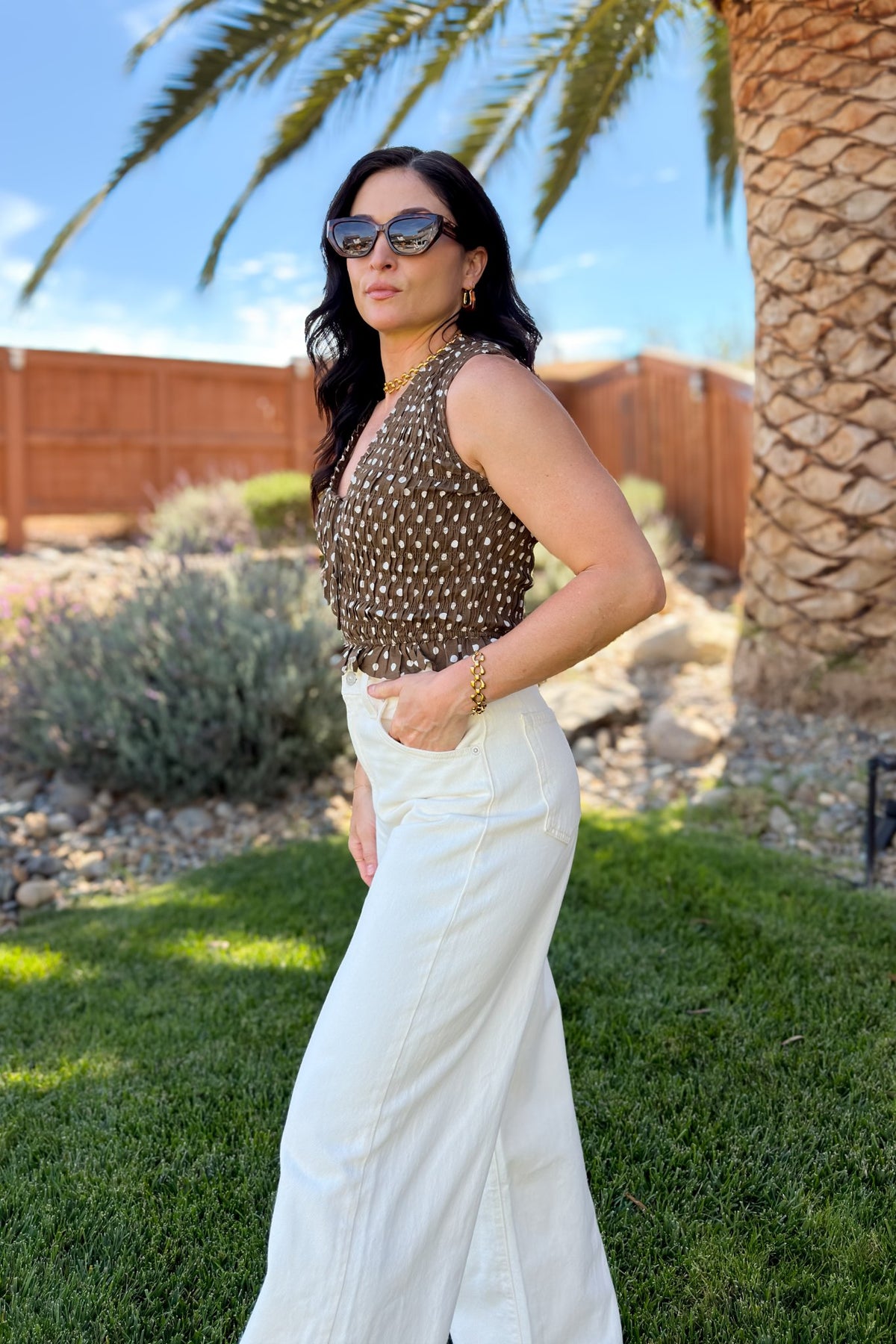 Close-up of a brown polka dot tie-front top showing the stretchy textured bodice and ruffle trim.