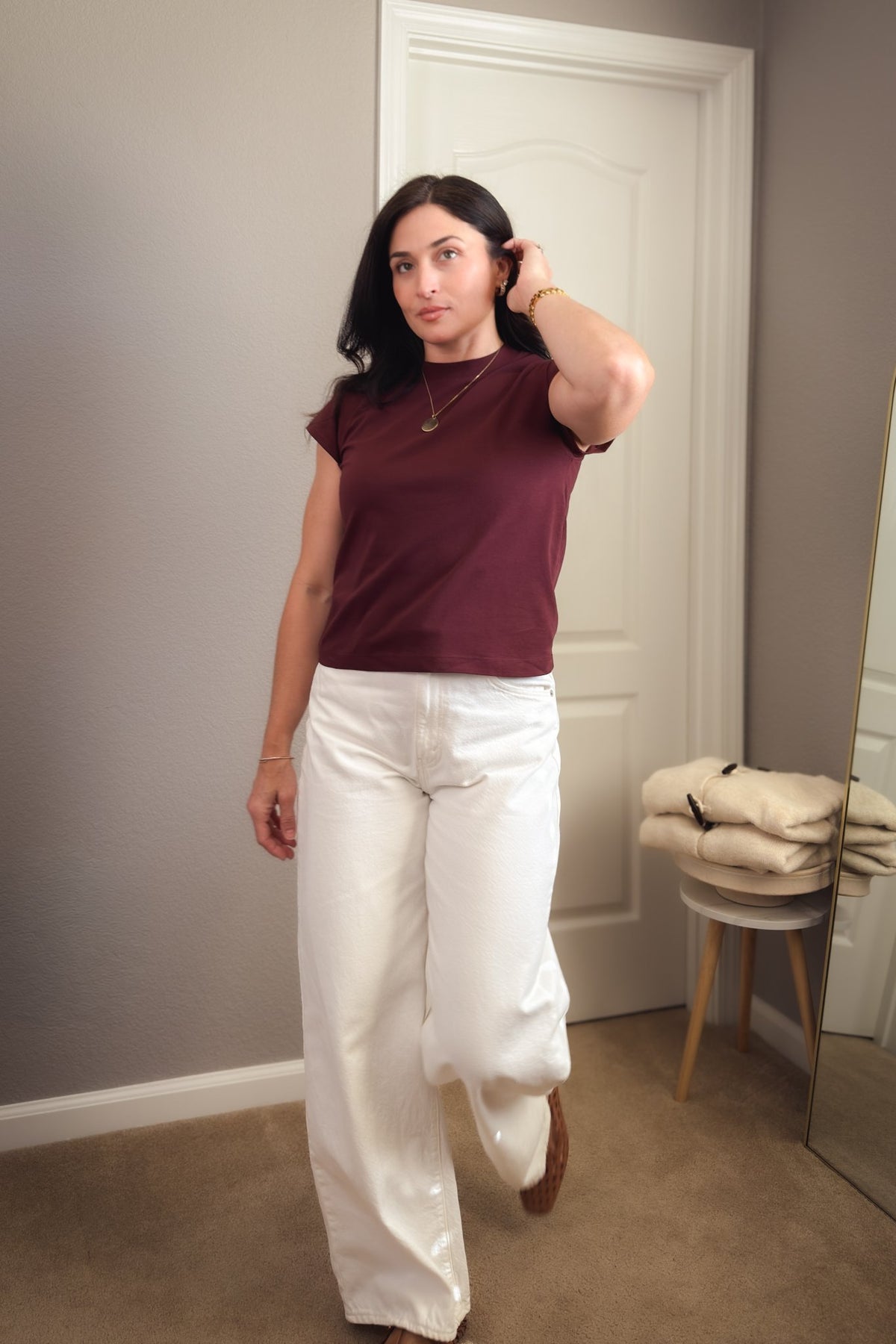 Burgundy crewneck top for women with structured cap sleeves and a polished fit styled with white jeans.