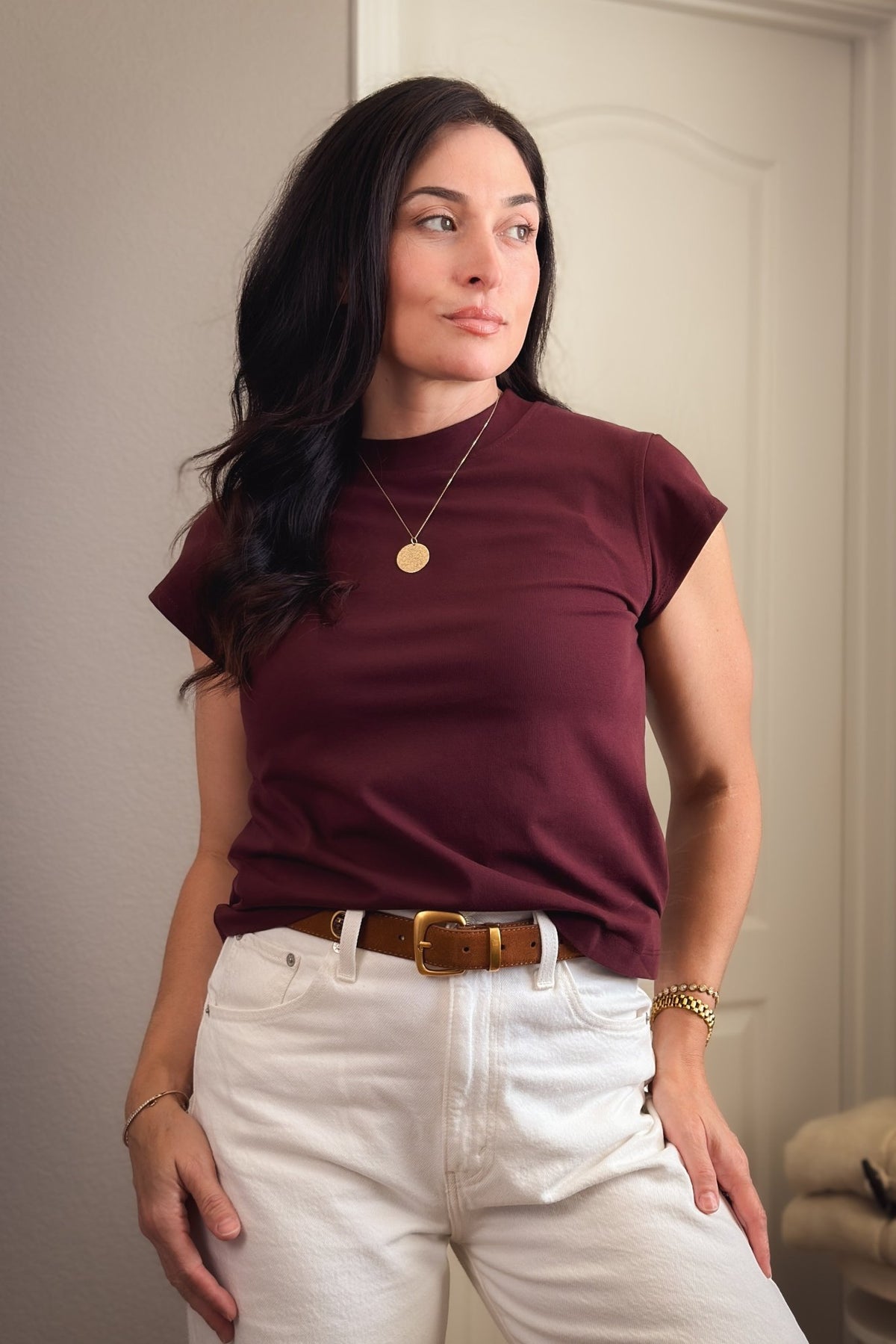 Burgundy cap sleeve crewneck T-shirt for women styled with white wide-leg jeans and a brown leather belt.