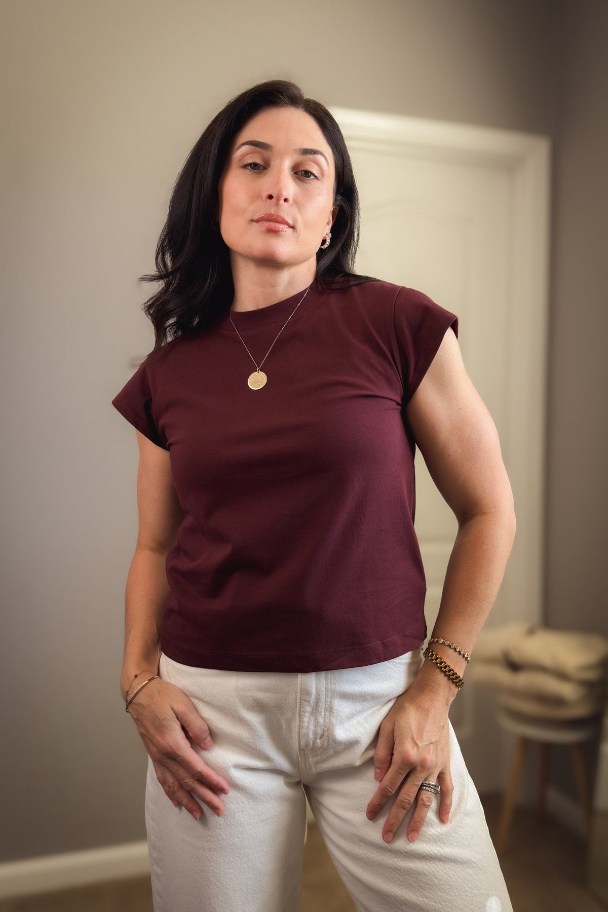 Burgundy cap sleeve crewneck T-shirt for women styled with white wide-leg jeans and a brown leather belt.