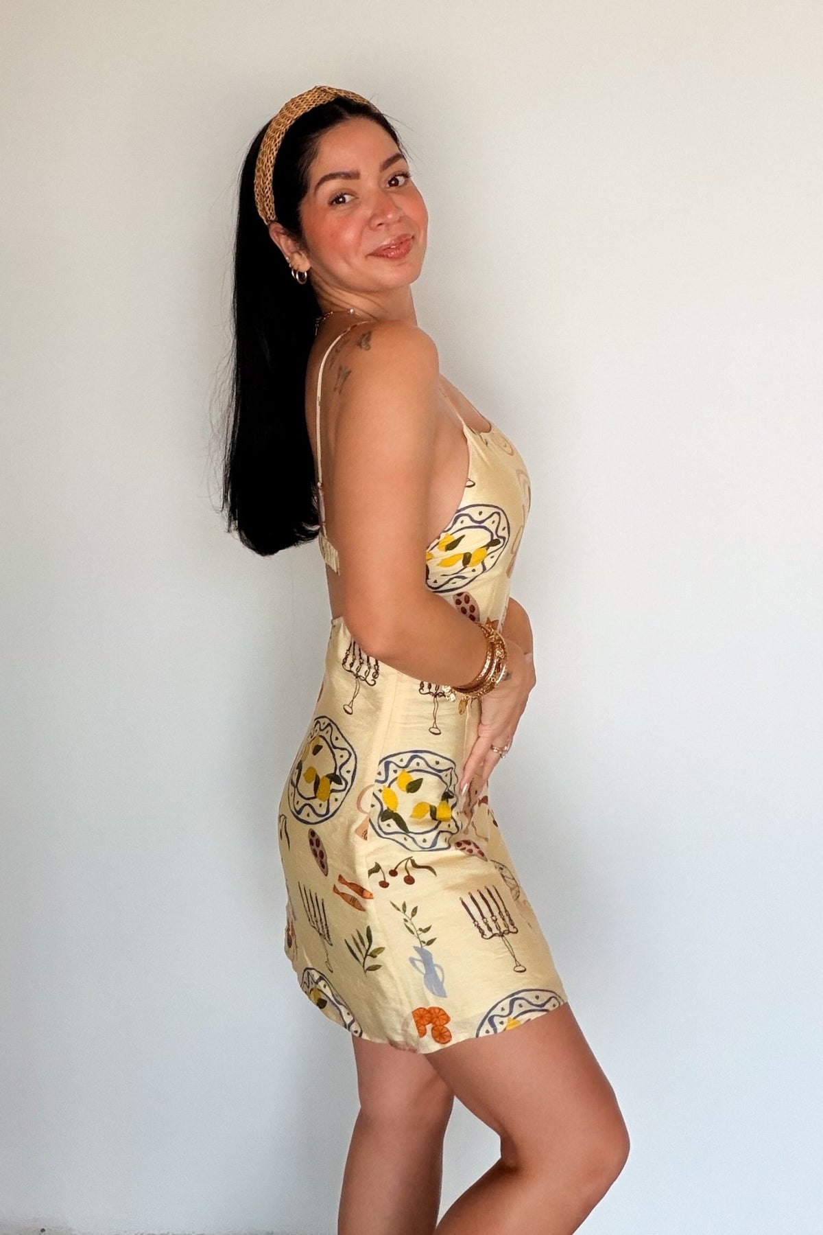 Side view of a butter yellow printed mini dress with adjustable straps, a fitted bodice and softly flared skirt.