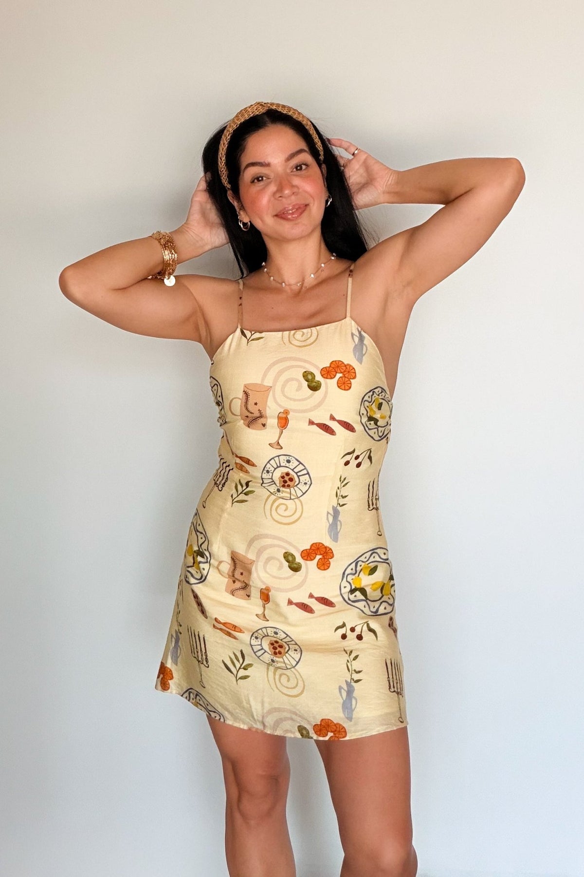 Full-length front view of the Butter Yellow Printed Mini Dress styled with layered necklaces, bracelets and a woven headband.