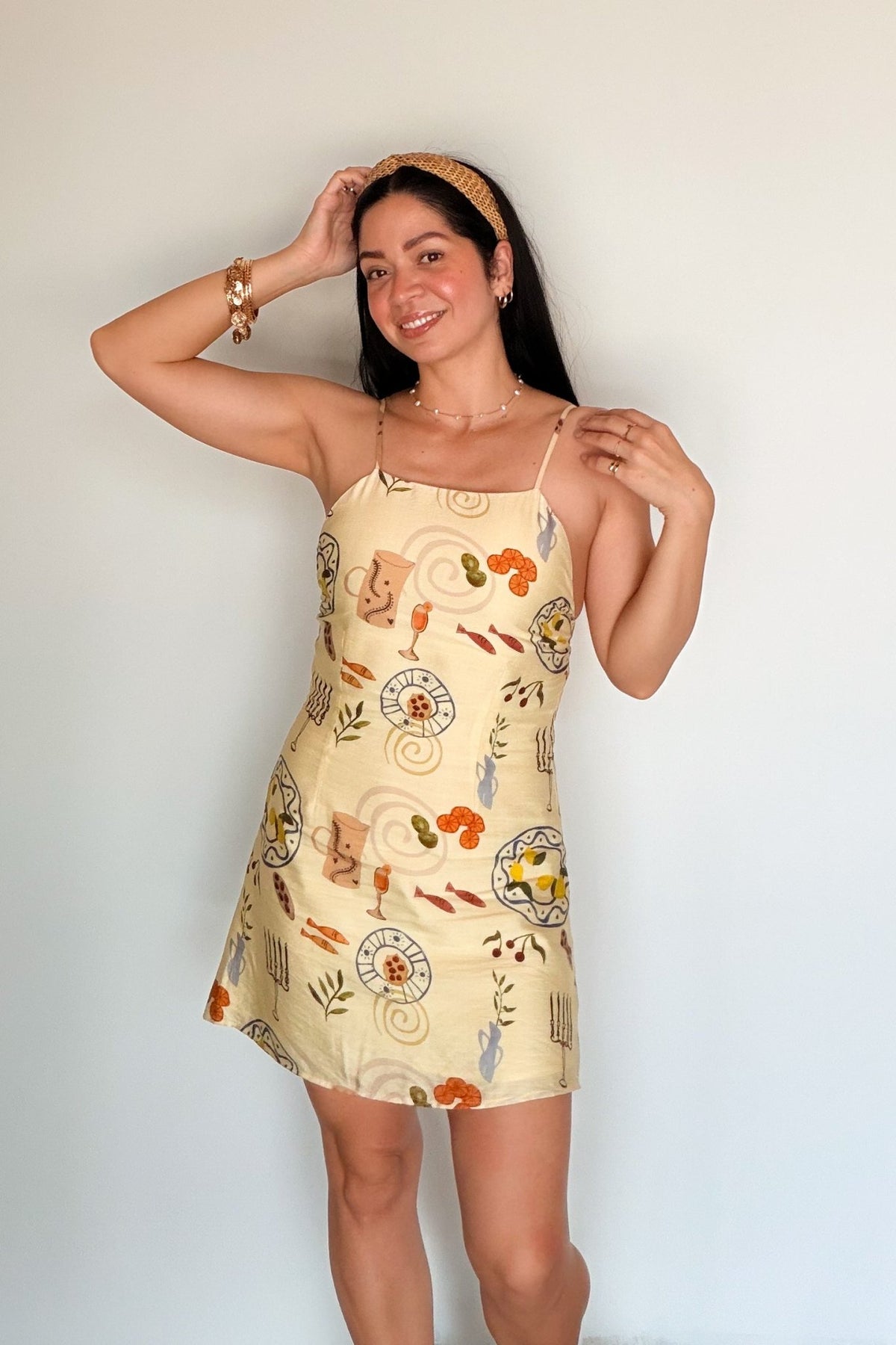 Butter yellow spaghetti strap mini dress with a relaxed A-line silhouette and whimsical food and tableware print.