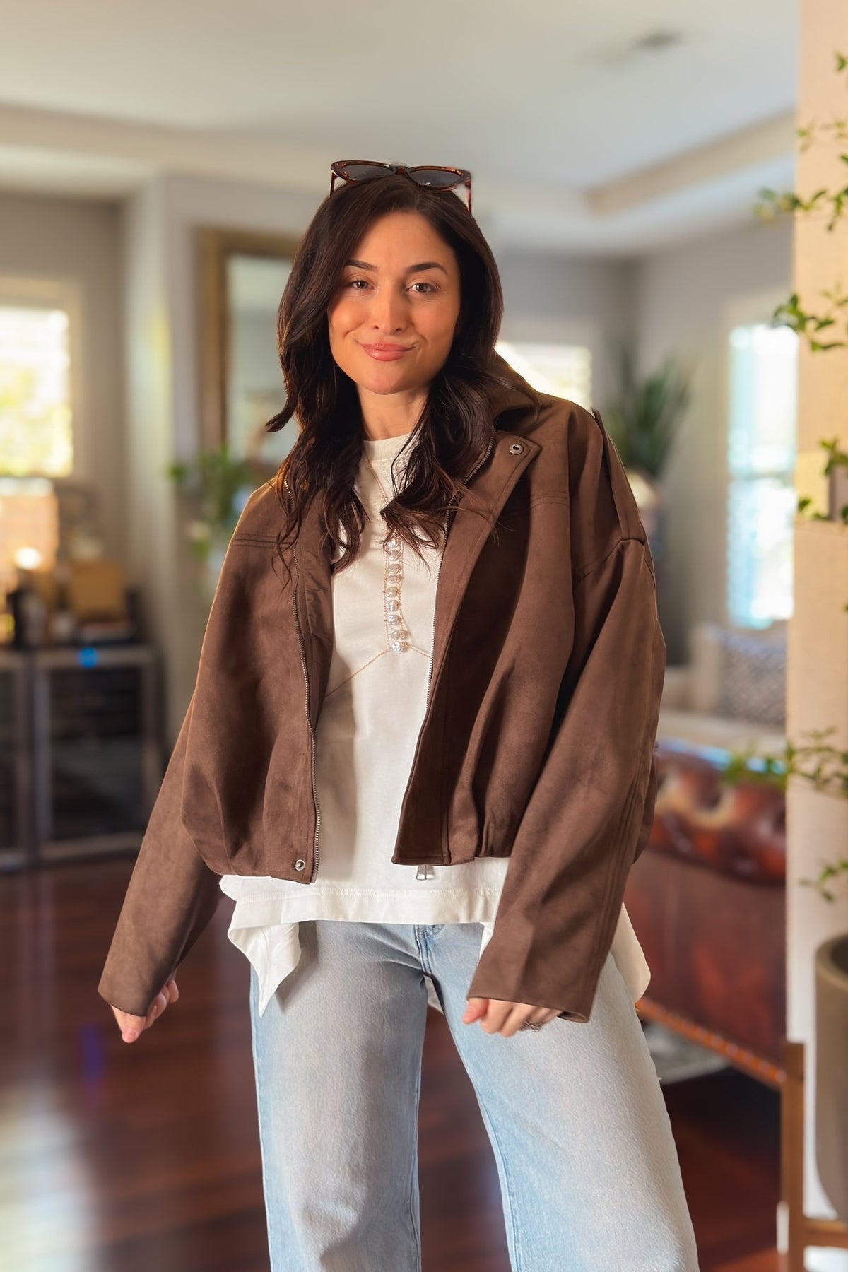 Close-up of chocolate brown faux suede bomber jacket showing the soft microsuede texture and relaxed construction.
