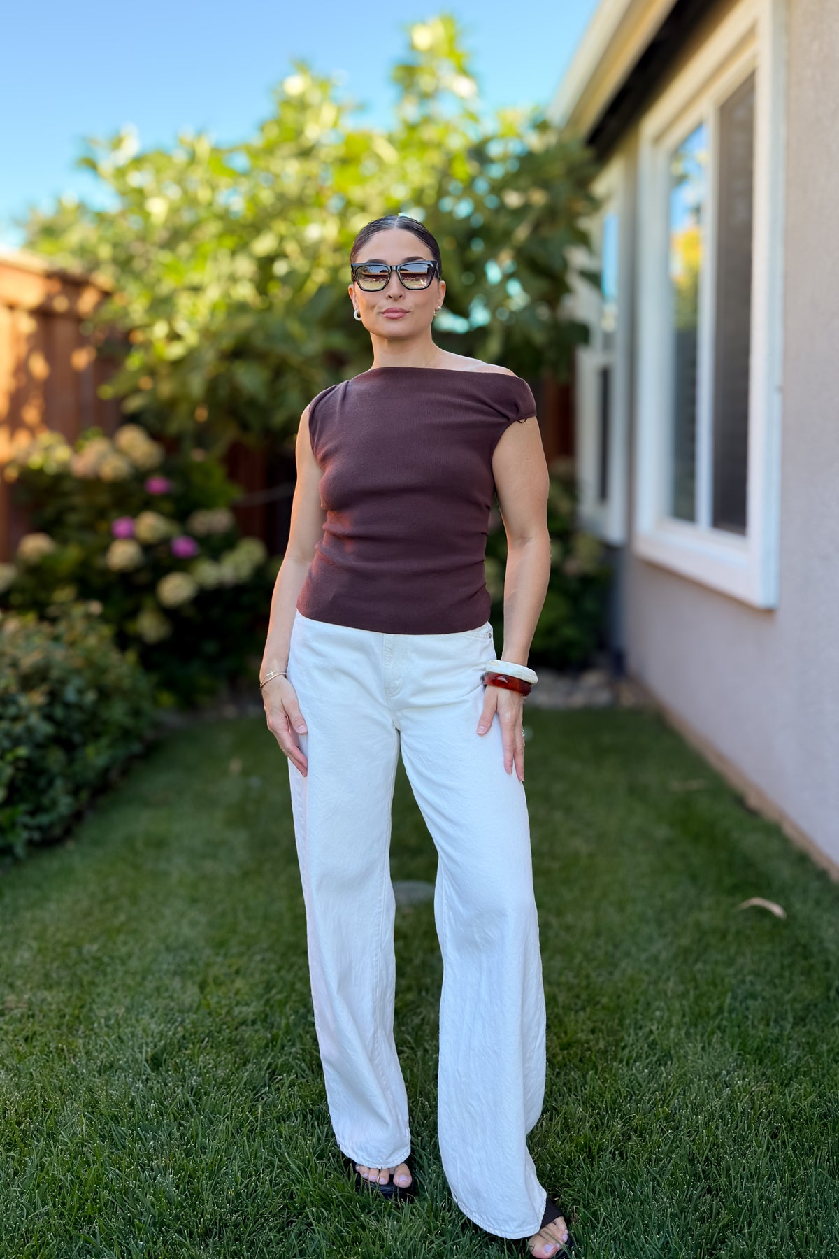 Back view of a soft chocolate brown knit top featuring an elegant off shoulder neckline and flattering fitted design.