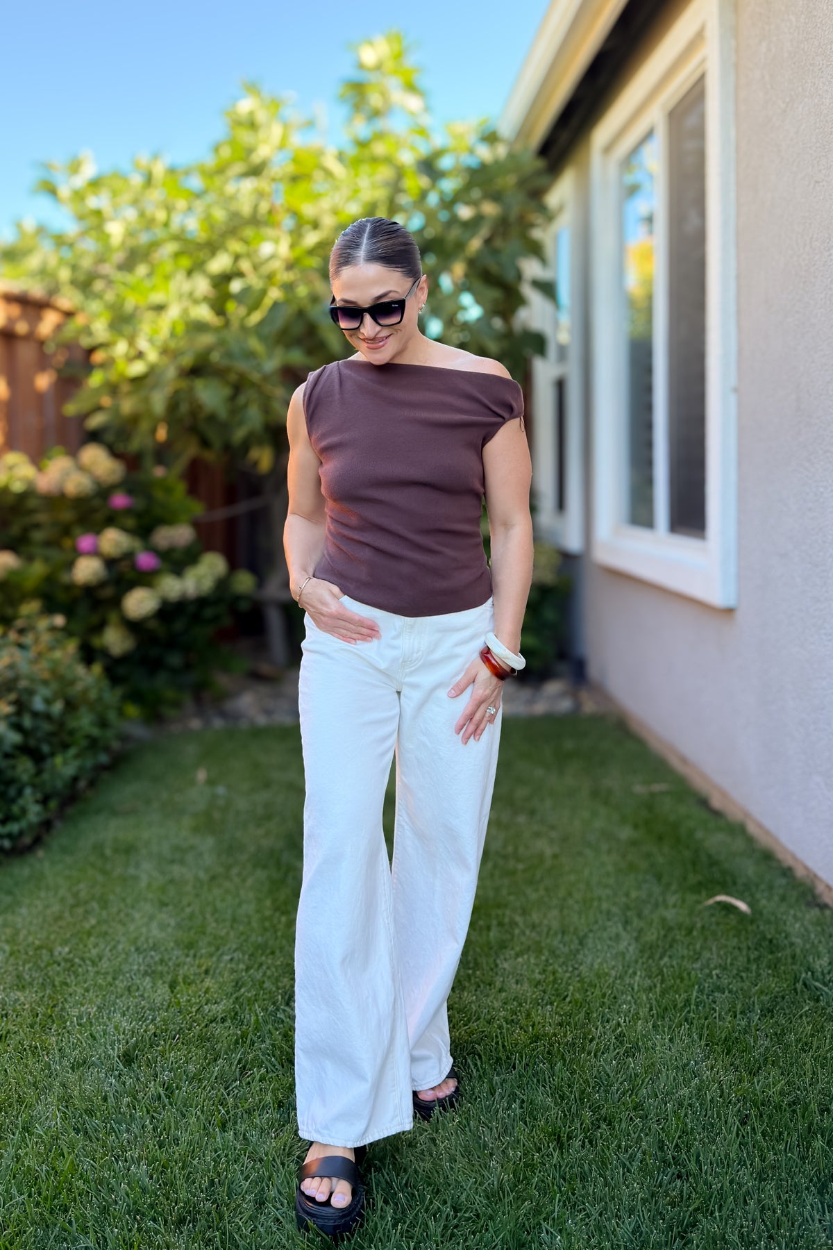 Lifestyle photo of a chocolate brown off shoulder knit top styled with neutral accessories for an elevated casual look.
