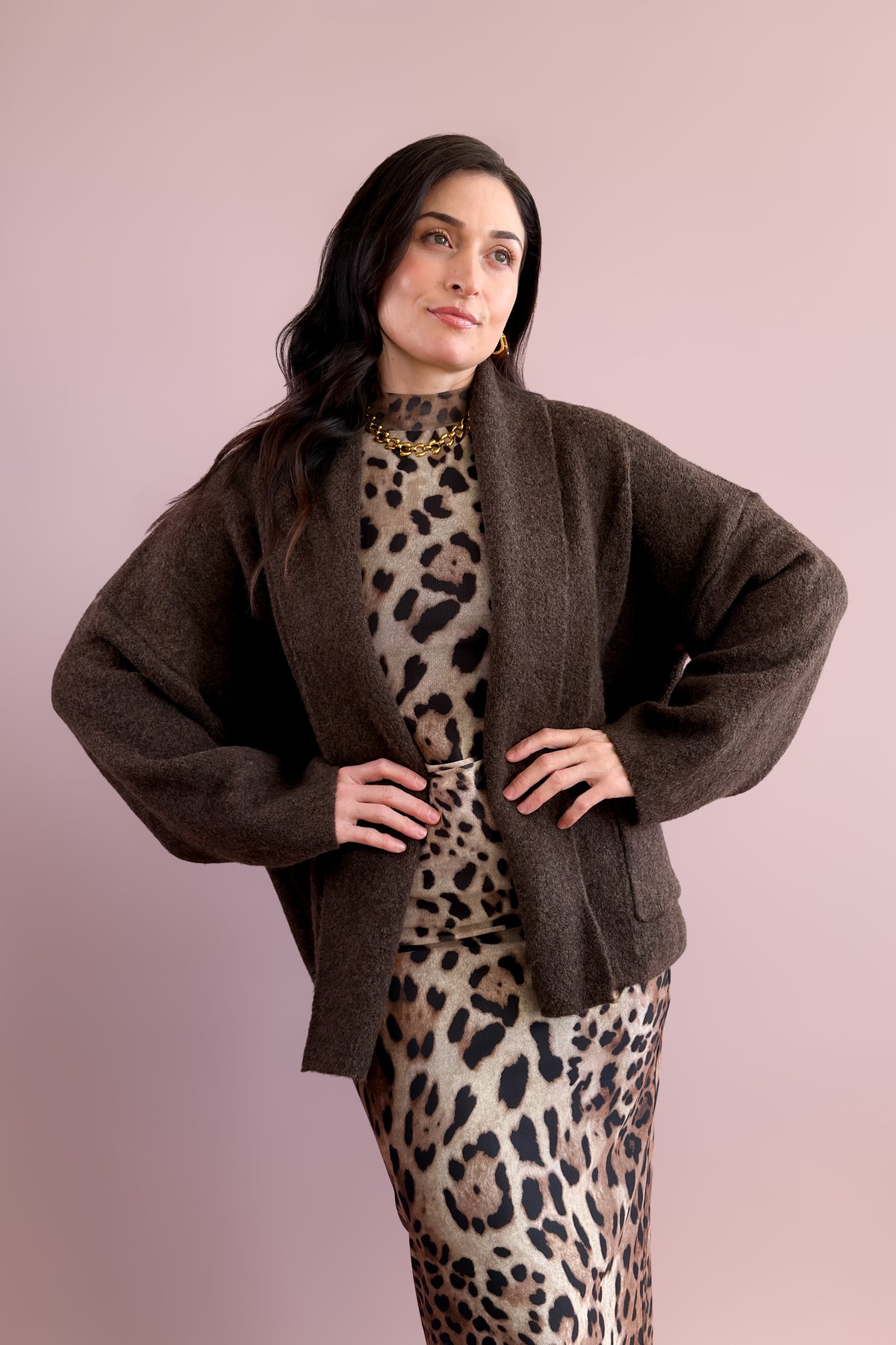 Chocolate brown cardigan sweater worn open with a leopard print midi dress and cream boots.