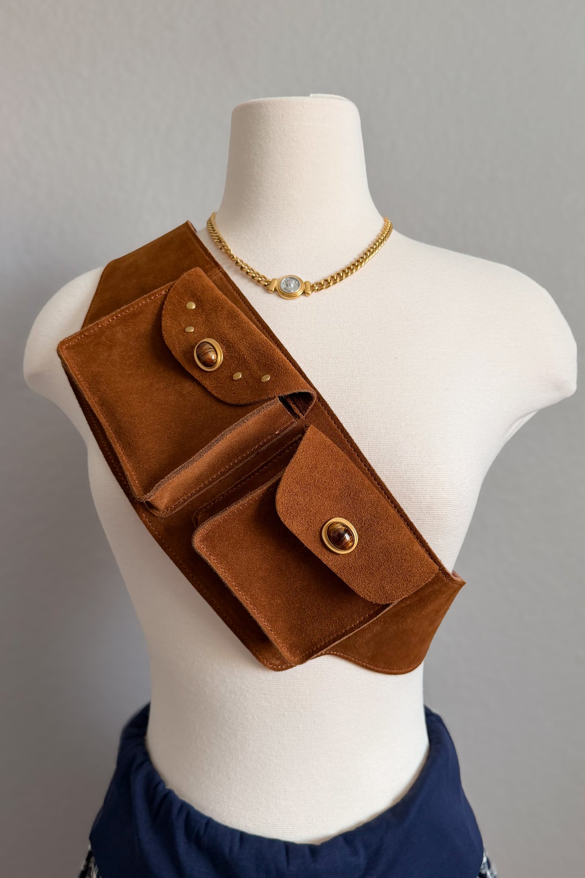 Cognac suede utility belt bag with two functional pockets, adjustable sizing and warm gold-tone hardware.