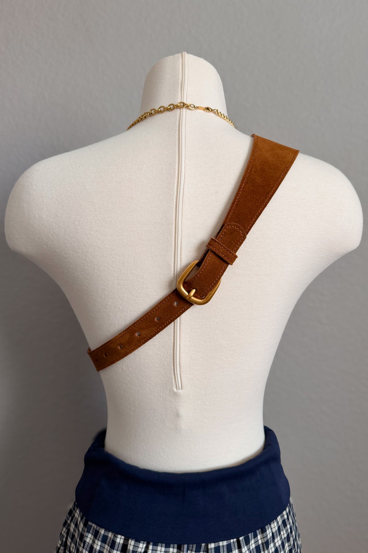Cognac genuine leather belt bag displayed crossbody on a mannequin, showing the wide strap, adjustable buckle and functional front pockets.