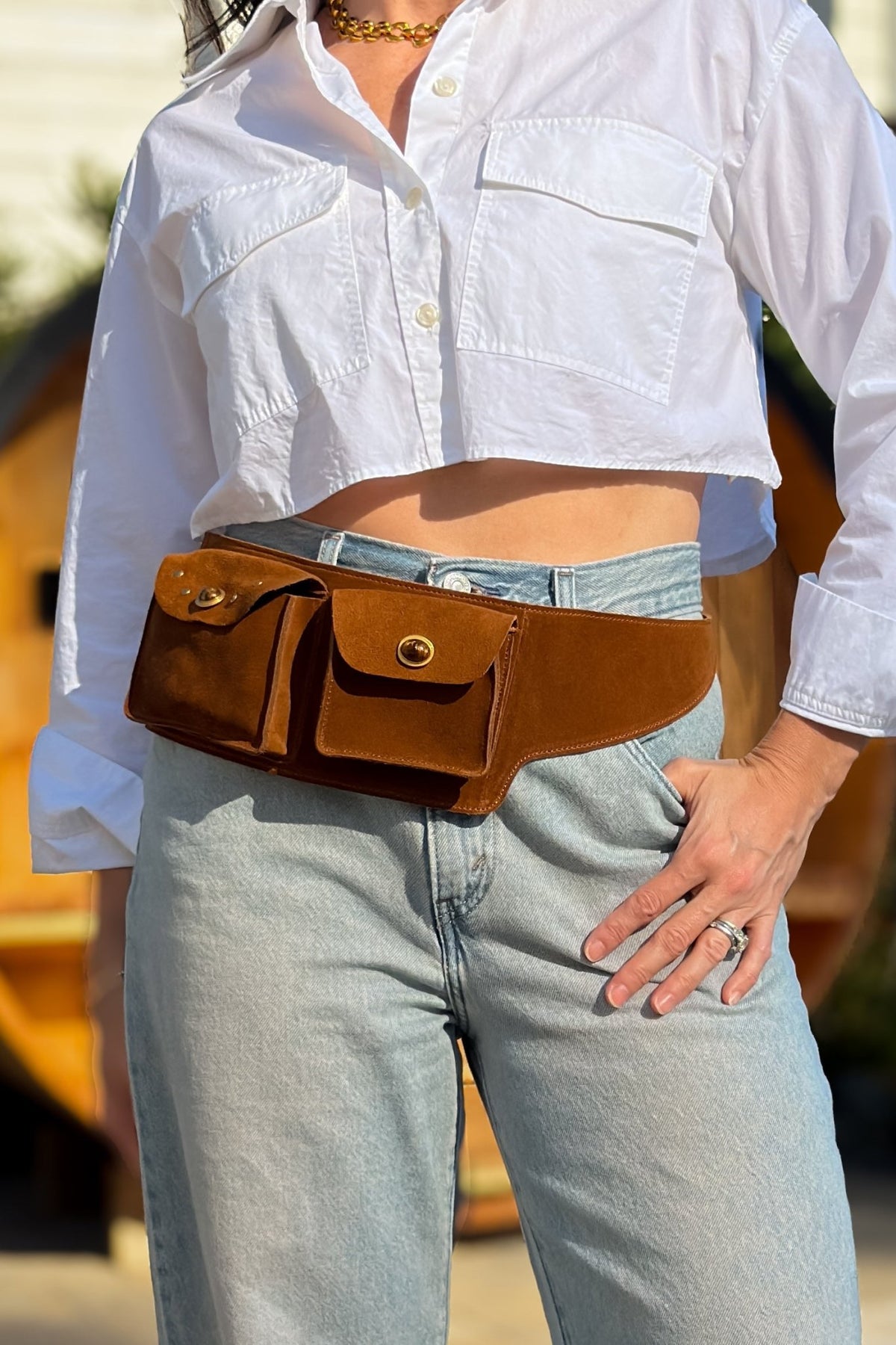 Cognac genuine suede leather belt bag styled at the waist with light wash jeans and a cropped white button-down shirt.