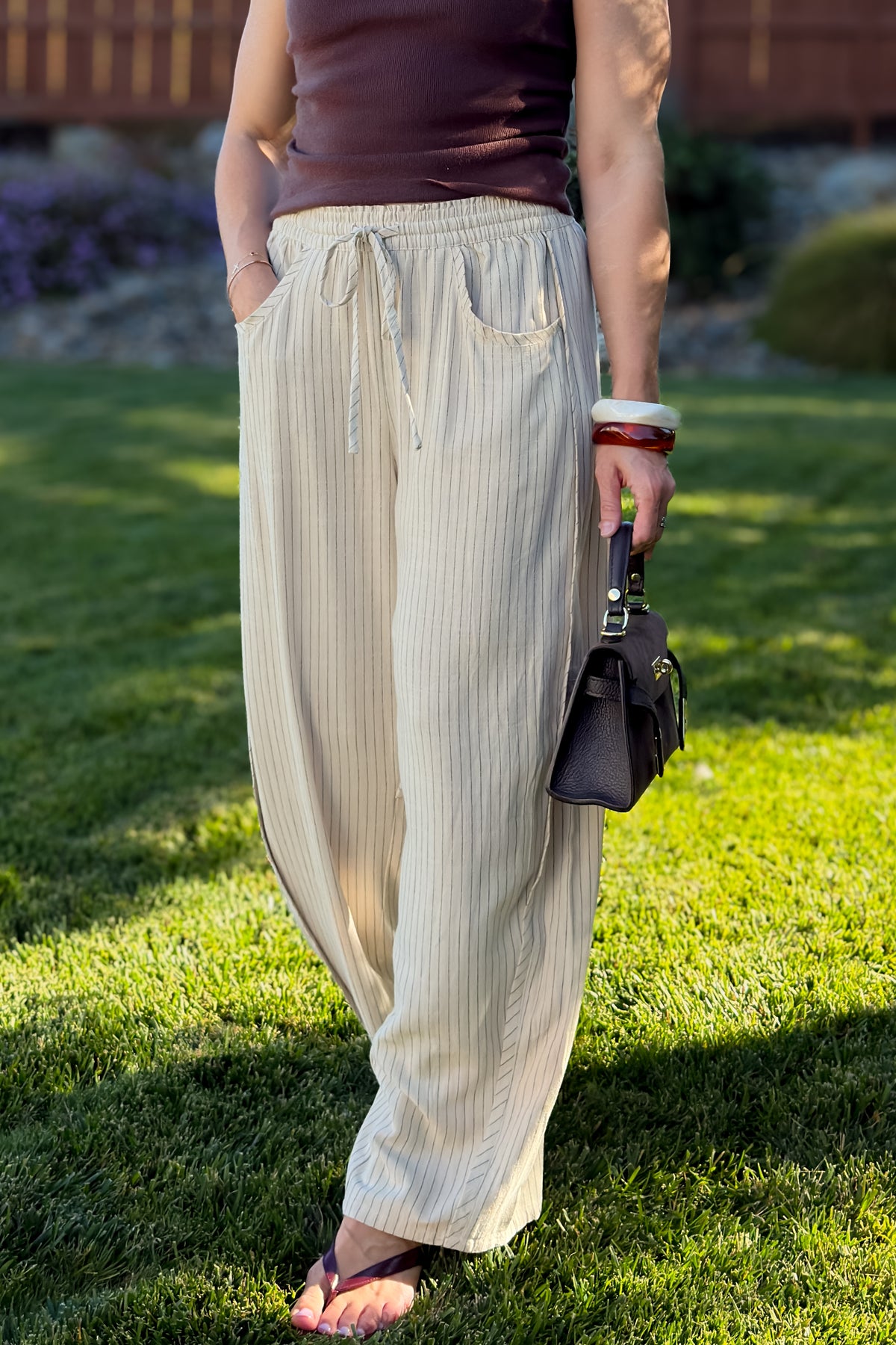 Back view of cream linen blend wide leg pants with subtle panel seam details and a comfortable elastic waistband.