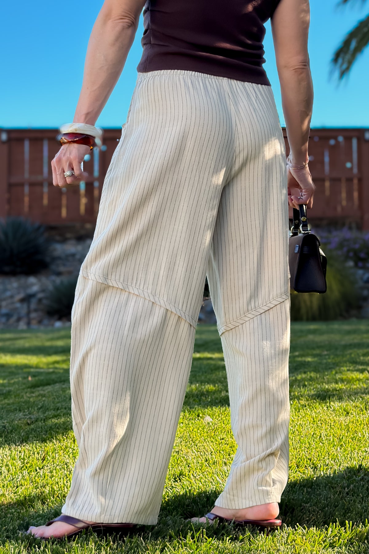 Cream rayon linen blend pants with thin vertical stripes, side pockets, and a breezy wide leg silhouette.