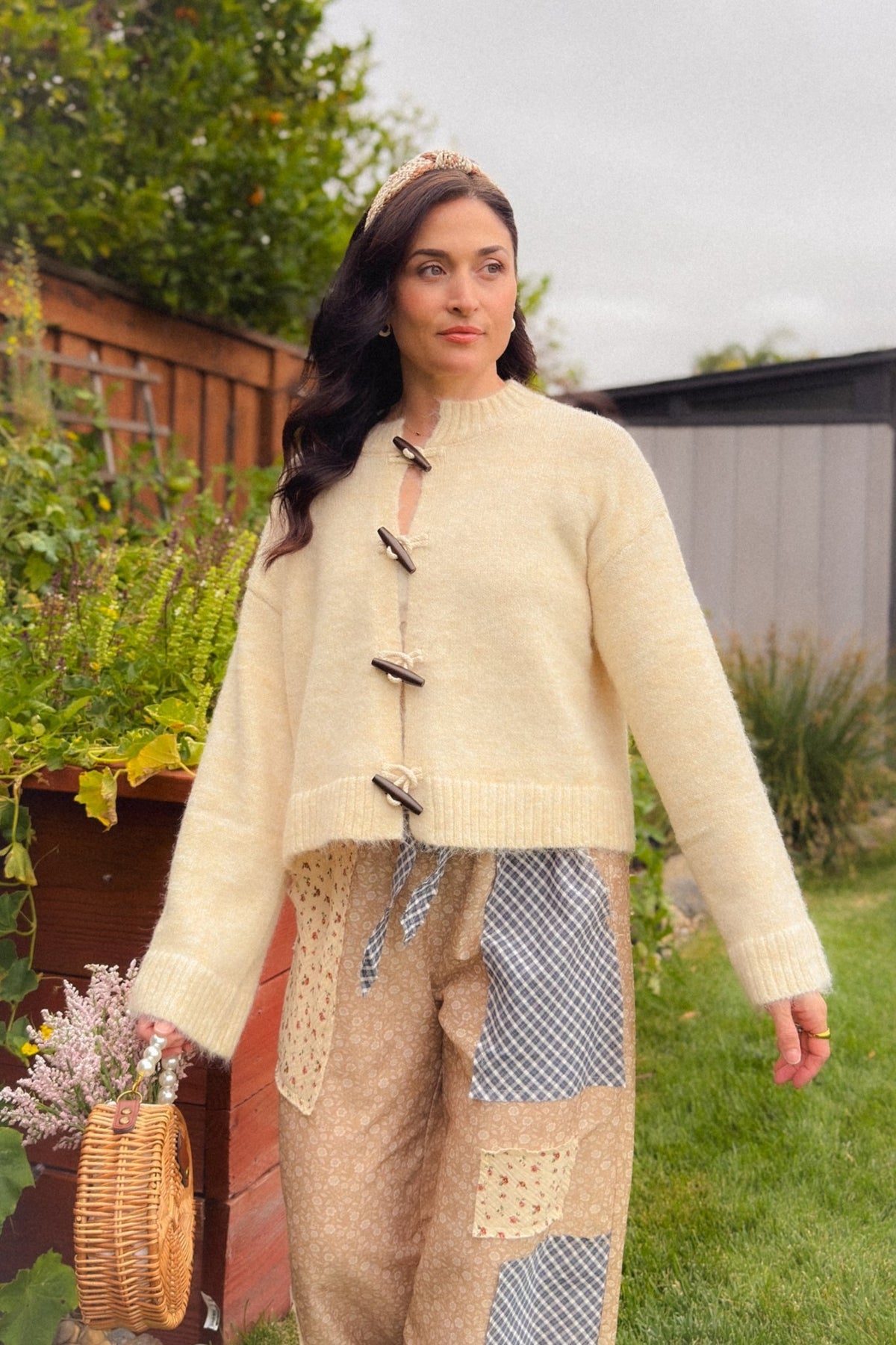 Cream wooden toggle knit cardigan with relaxed fit, wide sleeves and ribbed trim, styled with beige floral patchwork balloon pants for a soft fall outfit.