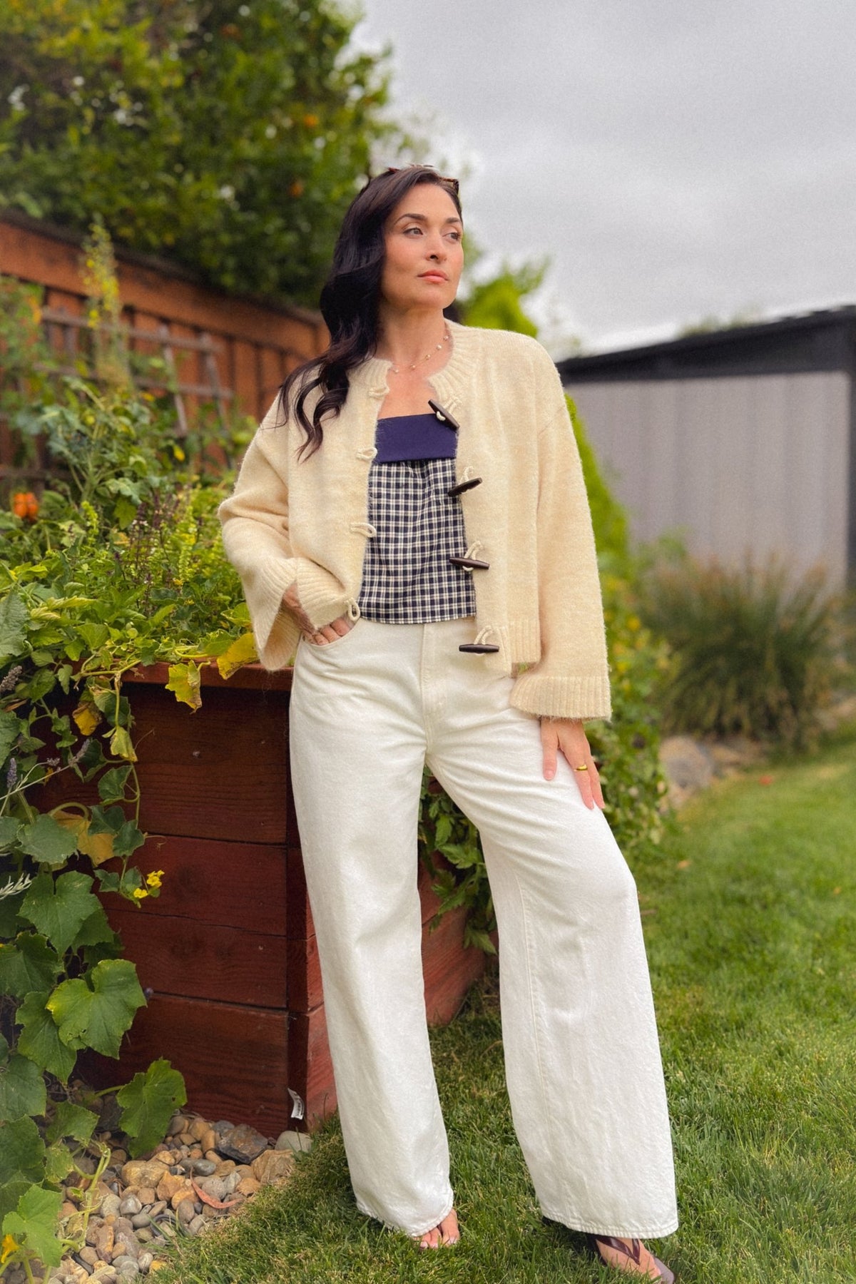 Relaxed cream knit cardigan featuring wooden toggles, ribbed trim and roomy sleeves, paired with patterned balloon pants.