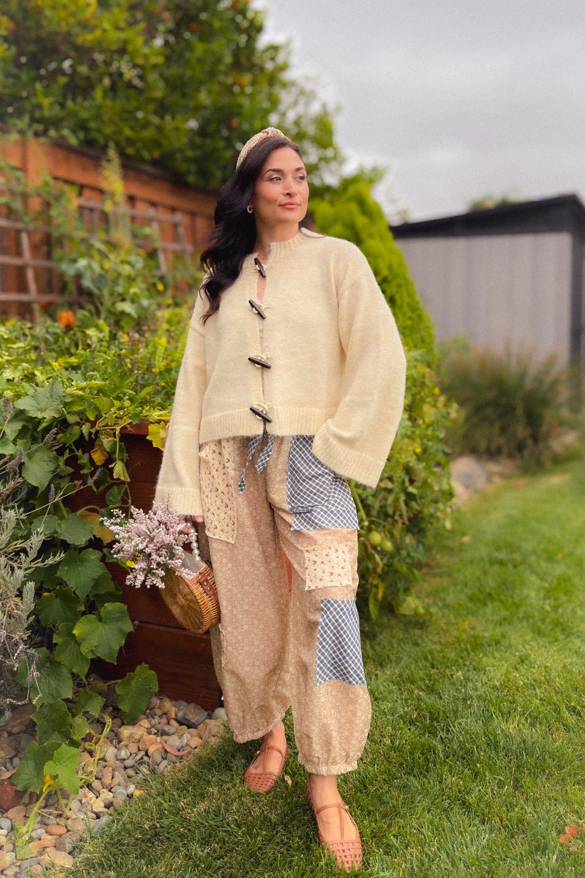 Woman wearing a cream knit cardigan with wooden toggle buttons, relaxed silhouette and wide sleeves for an easy transitional fall layer.