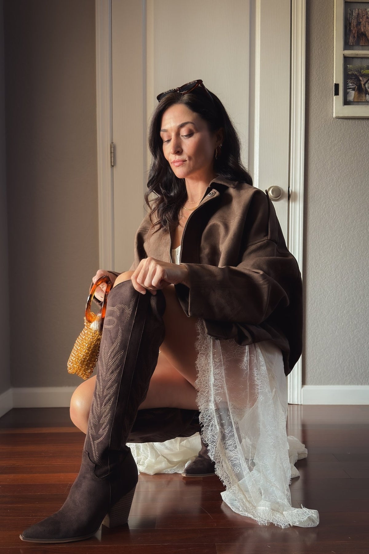 Close-up of dark brown embroidered western boots paired with an ivory lace layered dress and chocolate brown jacket for a romantic western look.