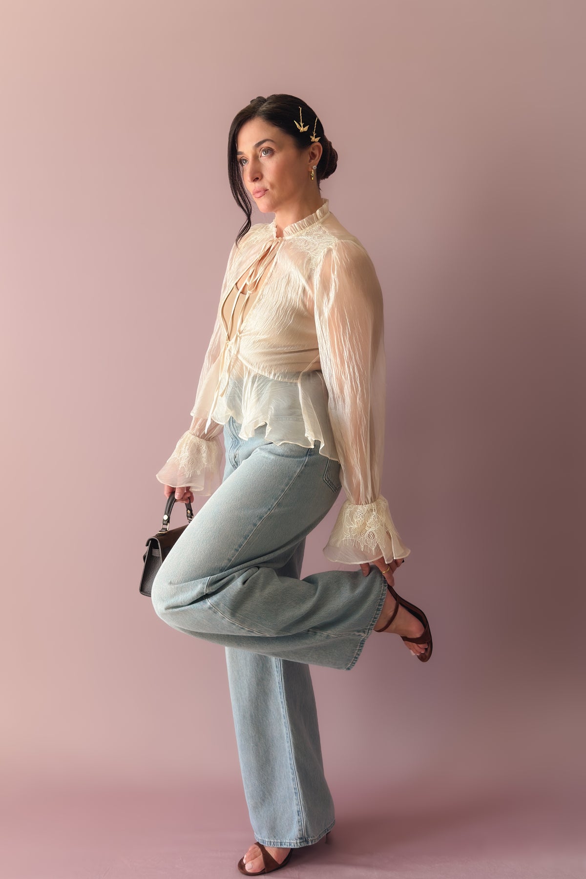 Close-up of ivory sheer blouse showing ruffled collar, lace trim and dramatic long sleeves