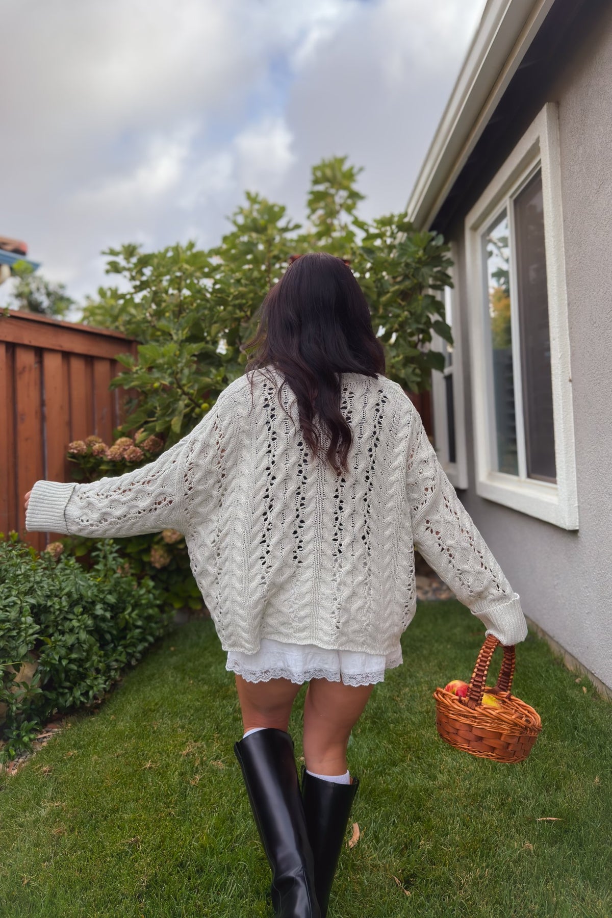 Women’s oversized Henley sweater in light gray styled with white shorts for a transitional fall look.