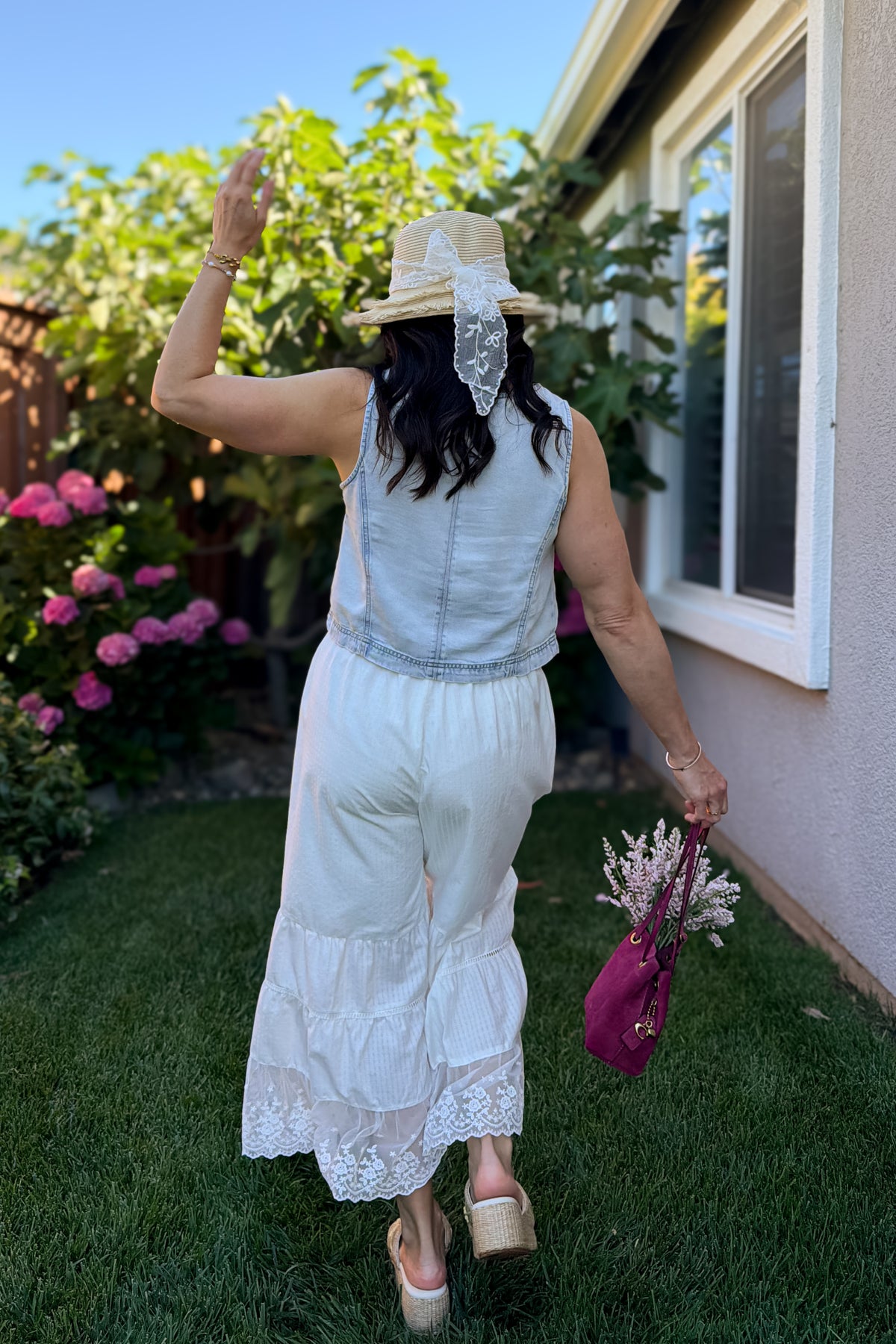 Women's light wash sleeveless lyocell tank top paired with a white tiered lace trim skirt for a feminine summer outfit.