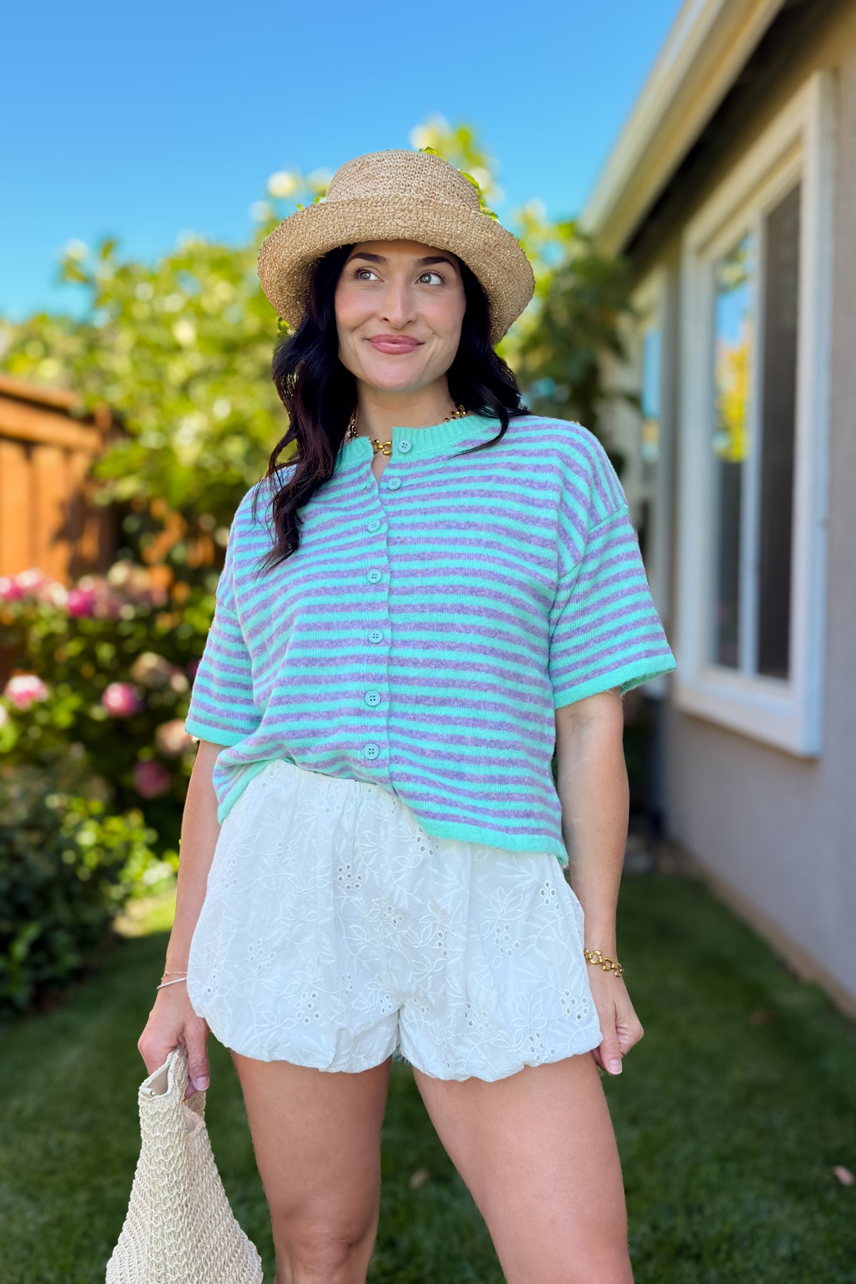 Back view of a lightweight mint striped knit cardigan with a relaxed boxy silhouette paired with white eyelet shorts and woven sandals.