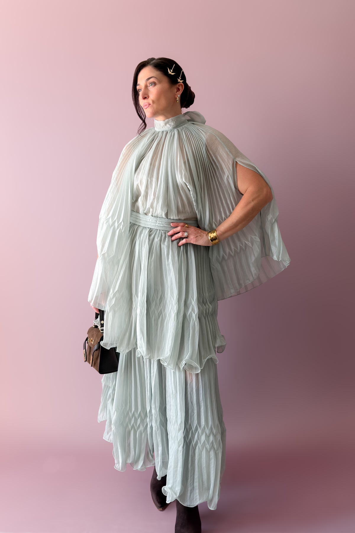 Back view of mint pleated cape top showing oversized bow and flowing semi-sheer pleated silhouette