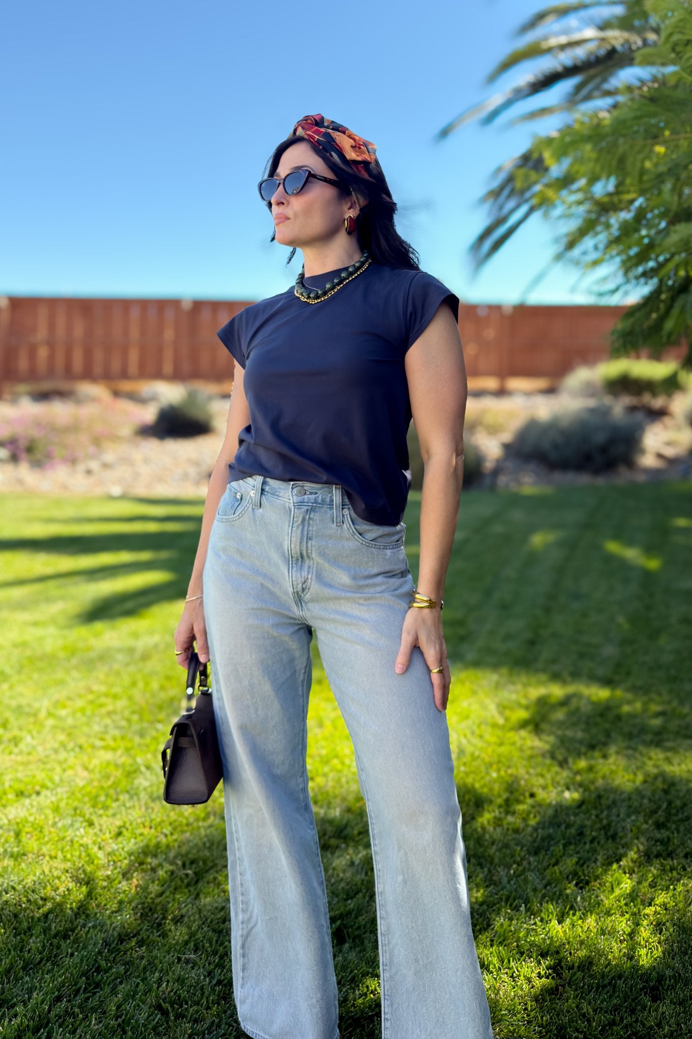 Navy blue cap sleeve crewneck T-shirt styled with light wash wide leg jeans and layered necklaces.