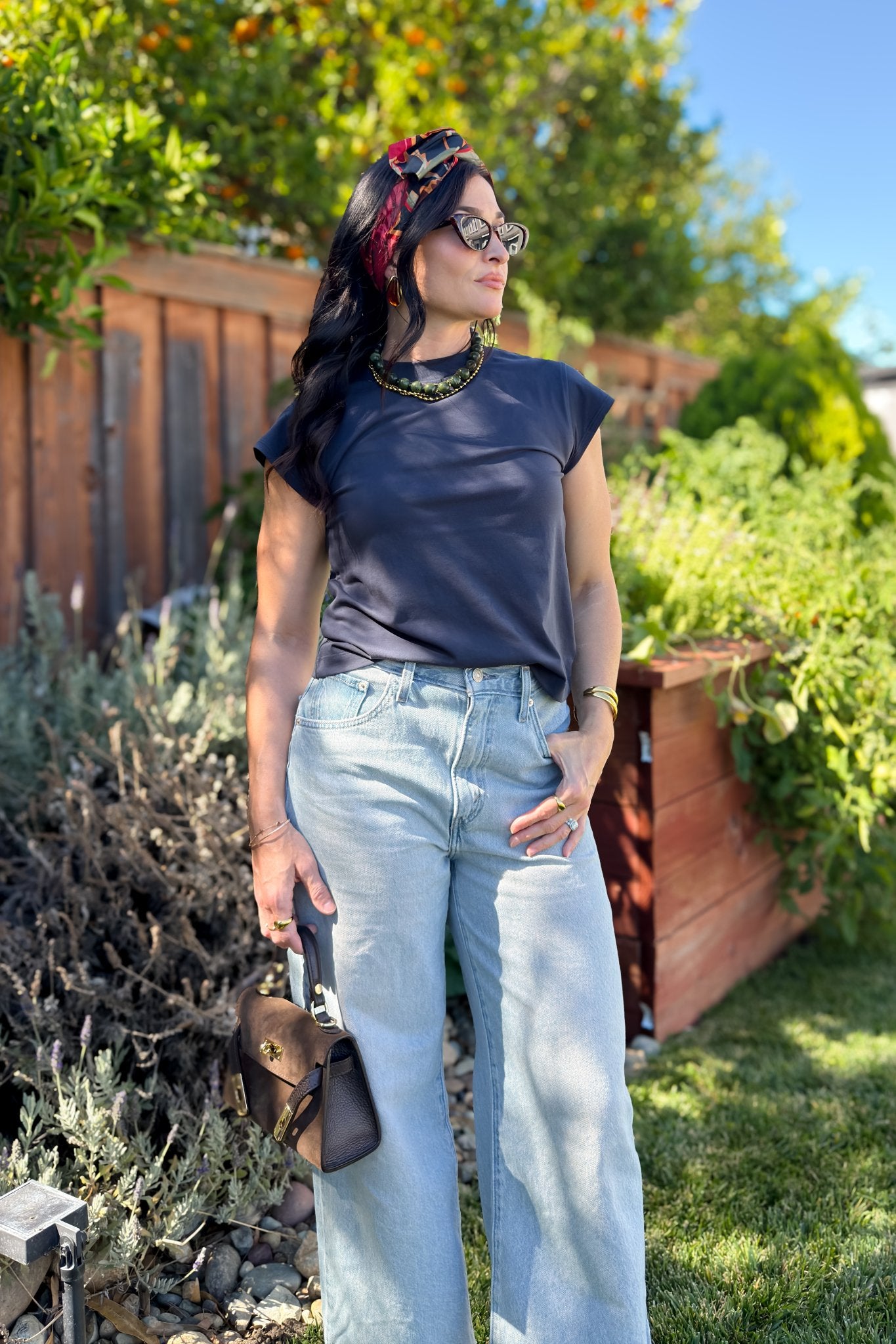 Navy blue cap sleeve crewneck T-shirt styled with light wash wide leg jeans and layered necklaces.
