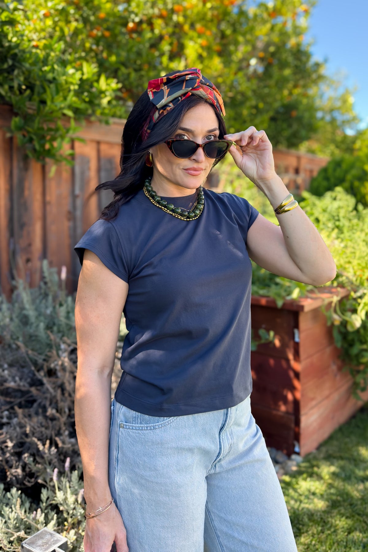 Navy blue cap sleeve top styled with jeans, a printed headband and statement jewelry.