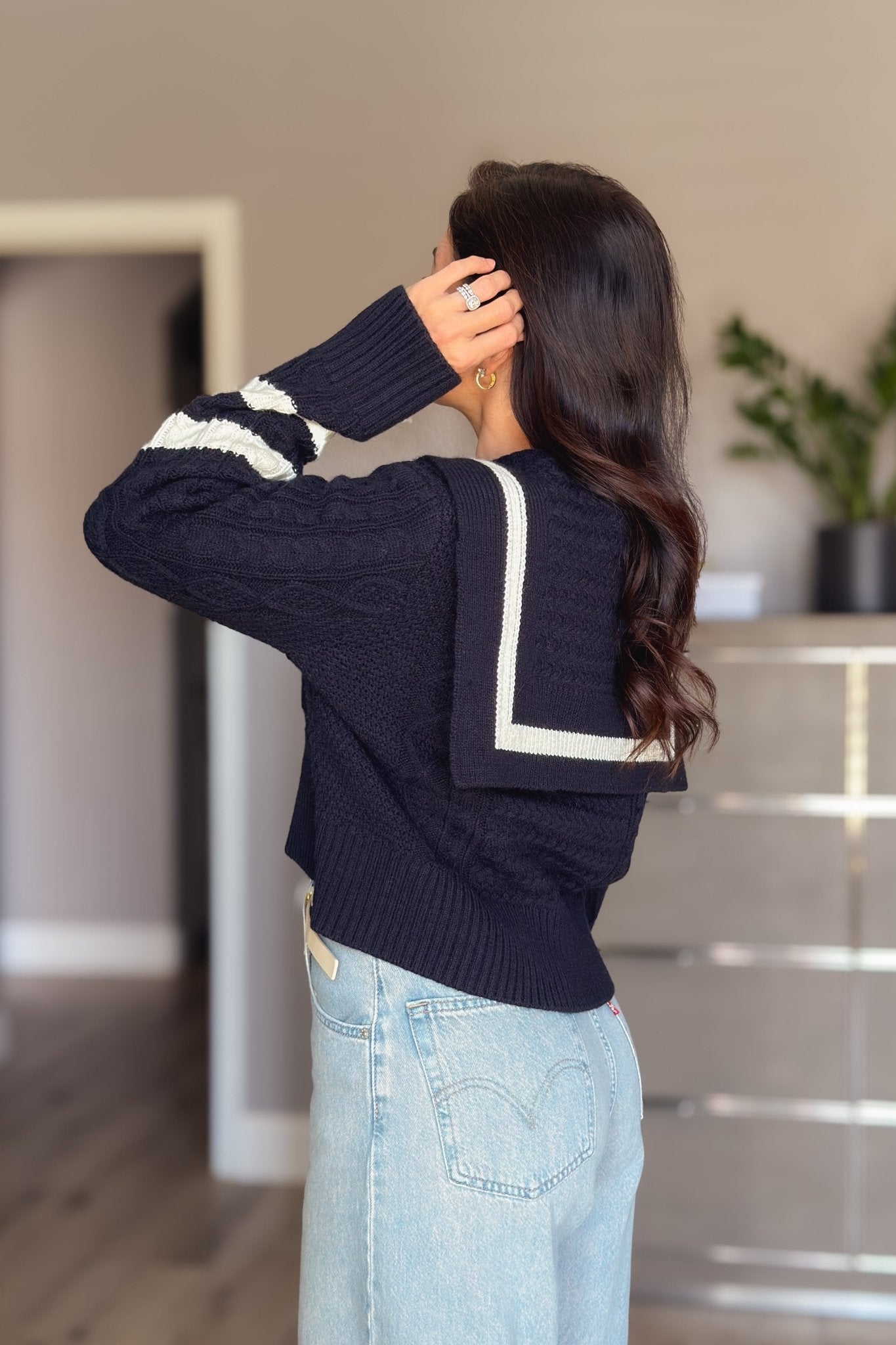 Women’s navy cable knit cardigan with ivory sailor collar, button front and striped sleeve detail styled with light wash jeans.