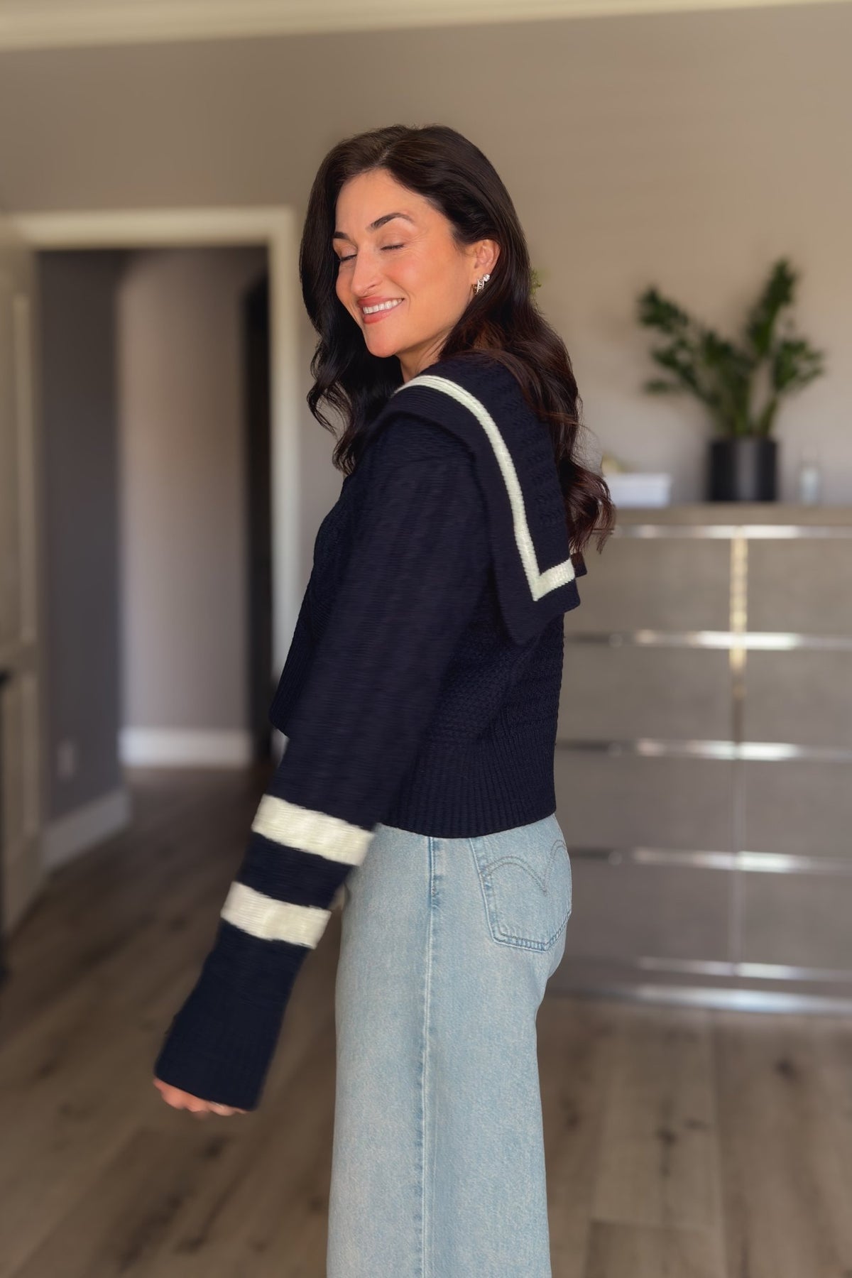 Women’s navy button-front sweater cardigan with wide sailor collar, ivory trim and long striped sleeves styled with denim.