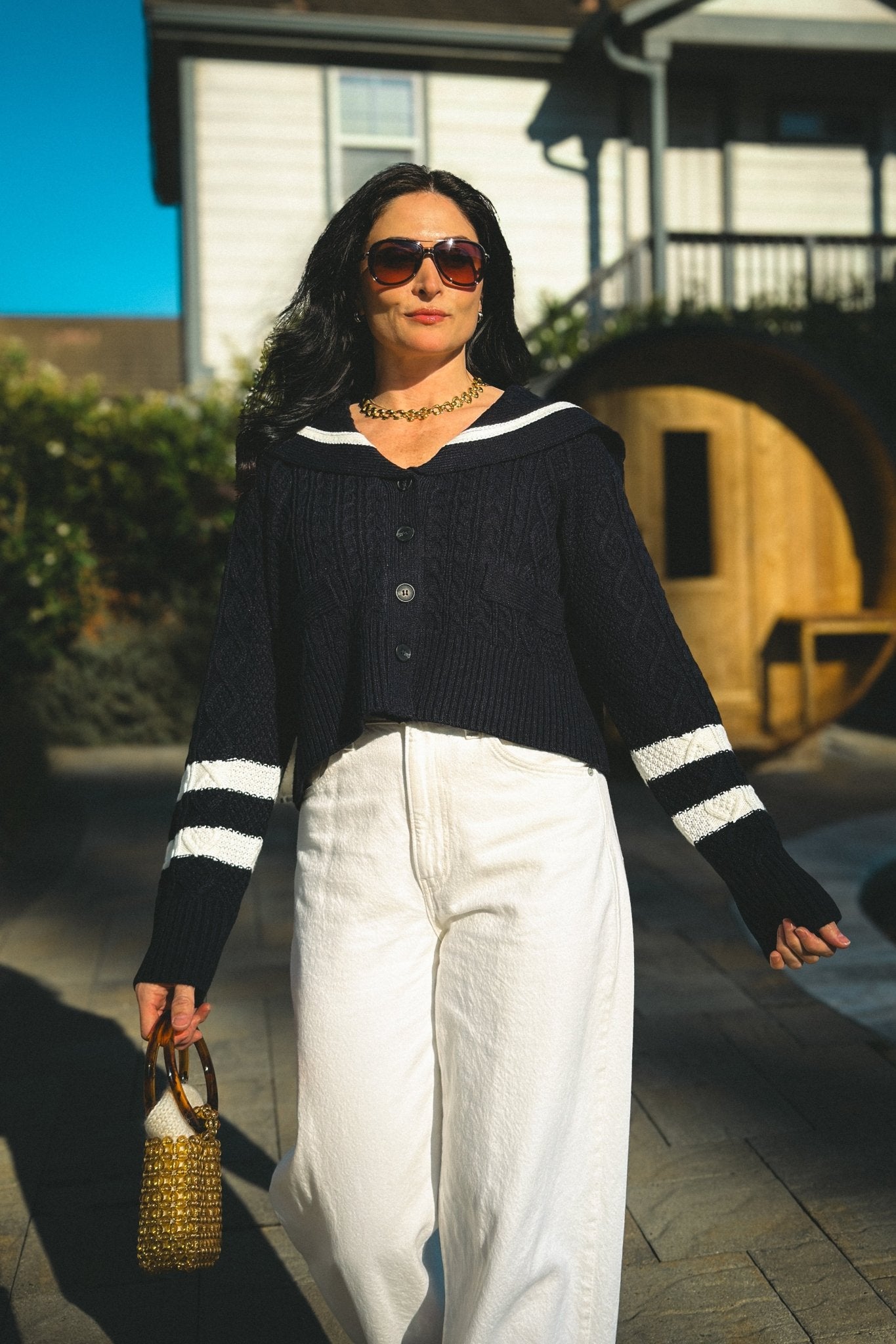 Navy cable knit cardigan sweater with ivory sailor collar and contrast stripe details, styled with cream wide leg pants.