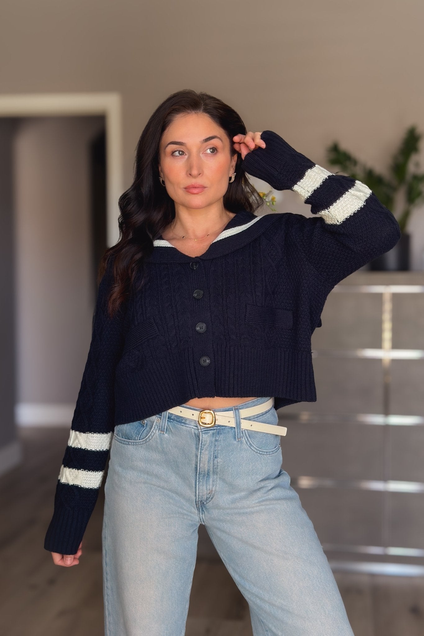 Women’s navy cable knit cardigan with ivory sailor collar, button front and striped sleeve detail styled with light wash jeans.