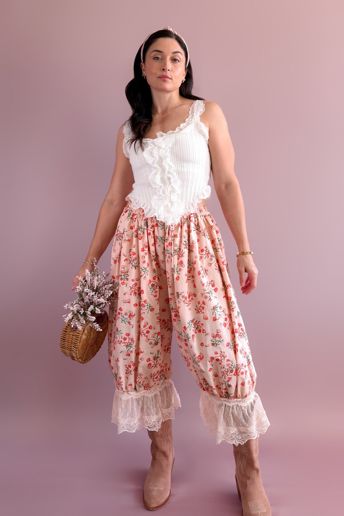 Close-up of women’s pink floral balloon pants with red flower print, drawstring waist, and ivory lace-trim cuffs