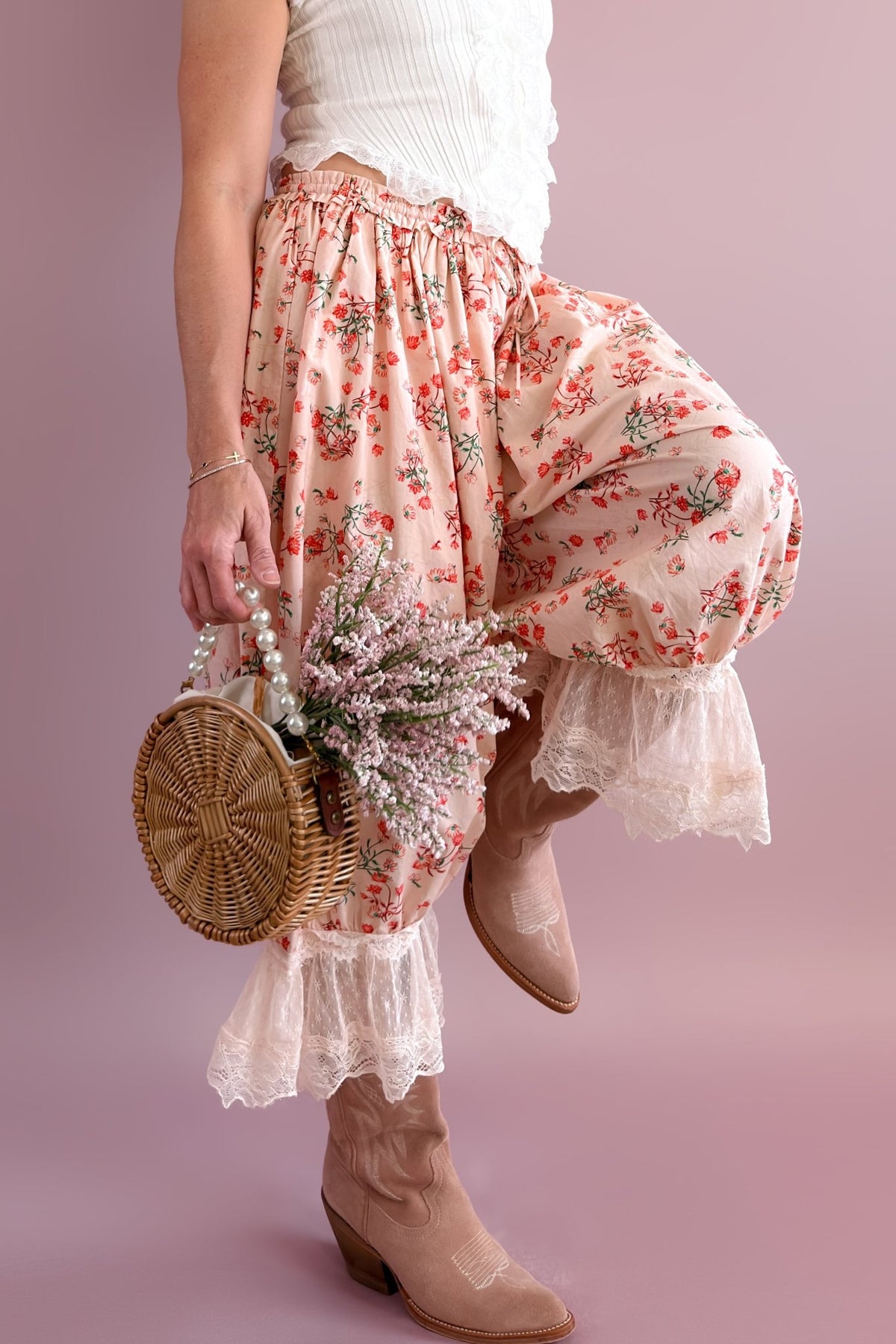 Full-length view of blush floral lace-trim bloomer pants styled with a white ruffle top and taupe cowboy boots