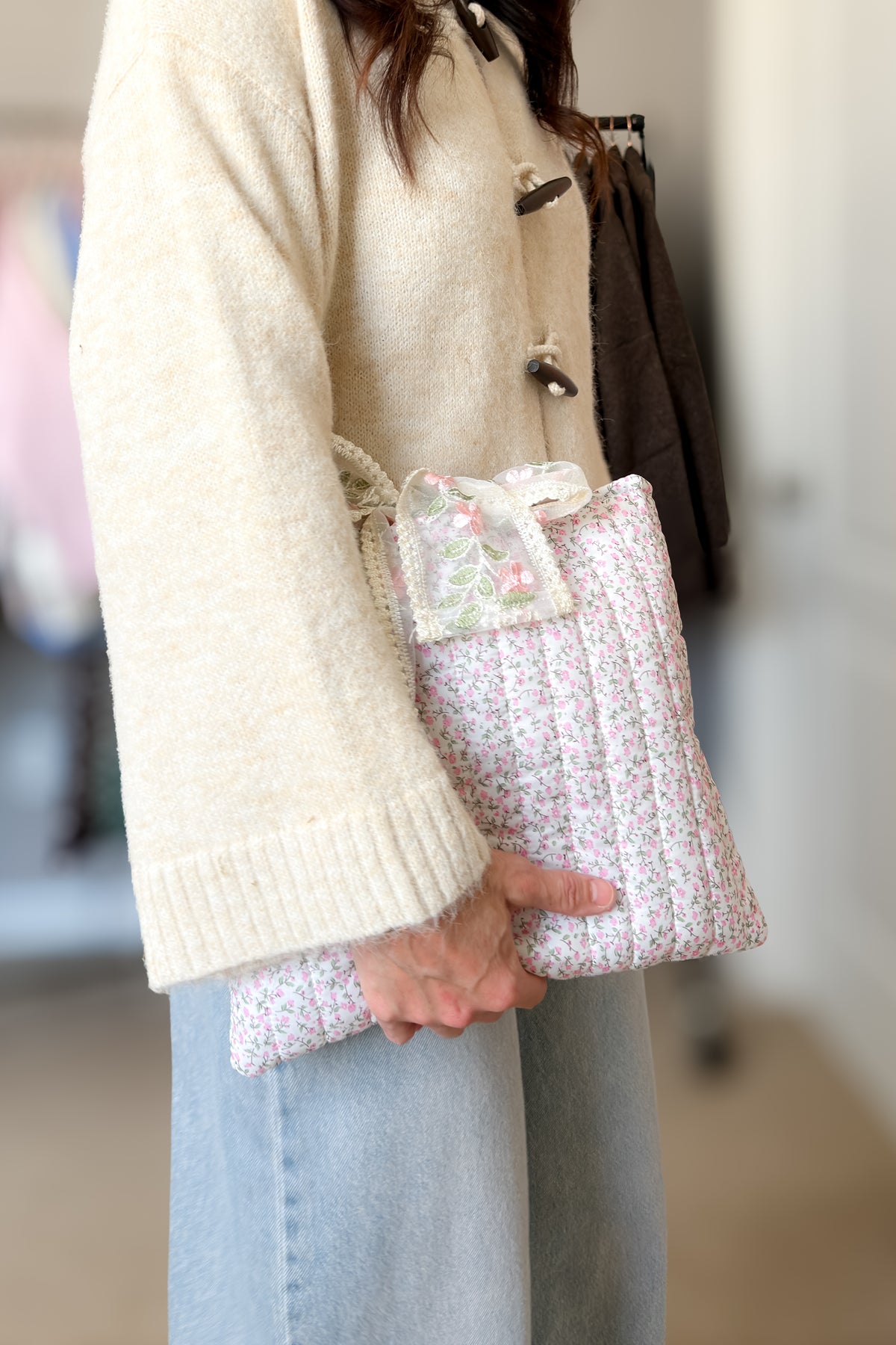 Feminine quilted Bible cover in pink floral print styled with a cream knit cardigan and light wash jeans