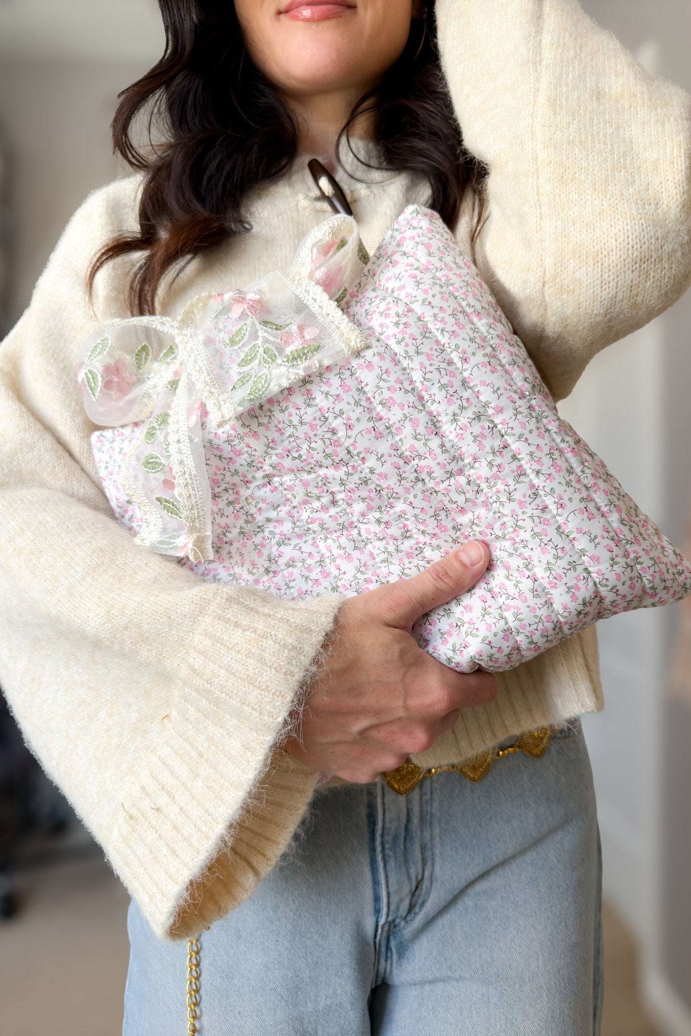 Woman carrying a pink floral quilted Bible cover with oversized sheer embroidered bow while wearing a cream toggle cardigan