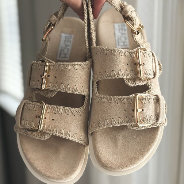 A pair of bohemian style sandals that resemble Birkenstock in a natural beige color with stitching around the straps