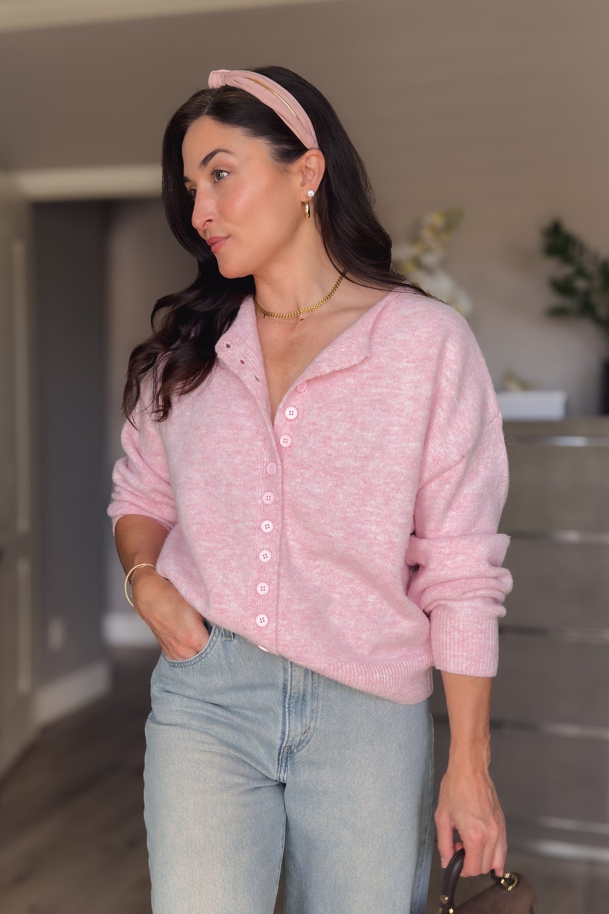 Close-up of soft pink cardigan sweater showing the heathered knit texture, ribbed hem, and matching pink buttons.
