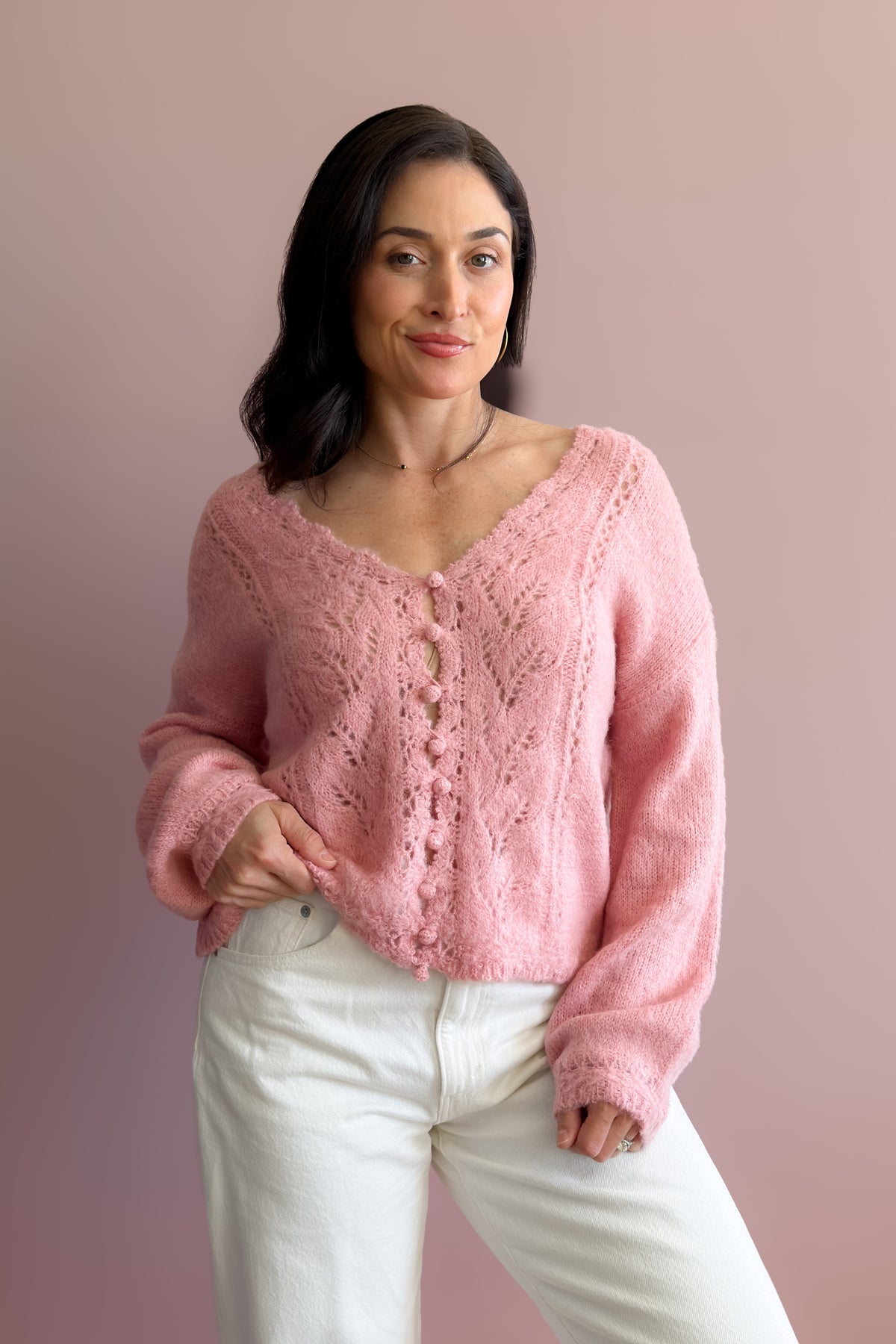 Soft pink pointelle knit V-neck sweater with decorative covered buttons and relaxed feminine fit