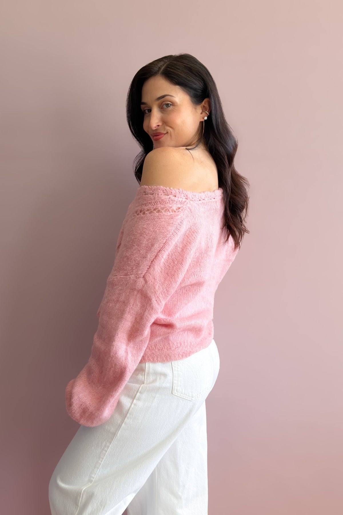 Close-up of soft pink pointelle sweater showing the textured knit, V-neckline, and covered button detail
